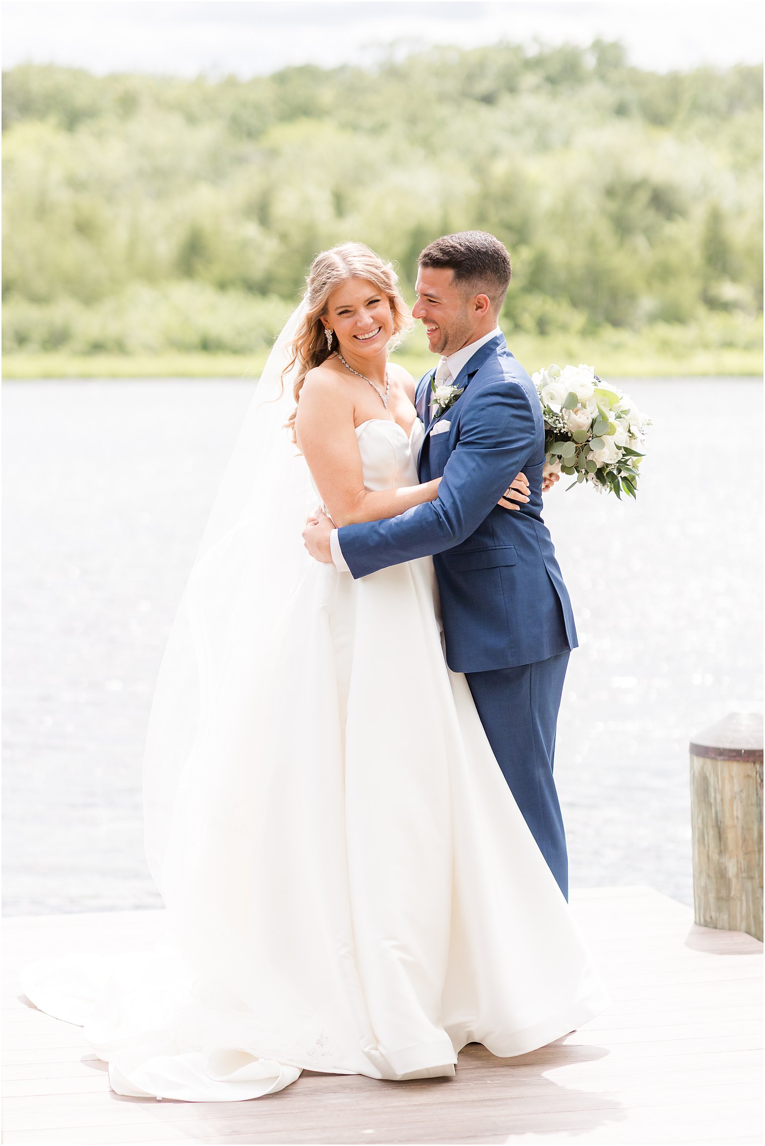 groom smiles at bride on dock at The Mill Lakeside Manor