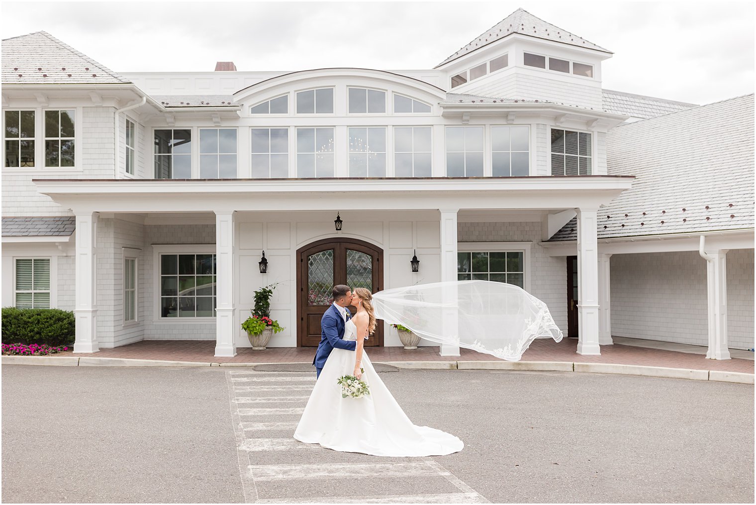 newlyweds kiss while bride's veil floats behind them