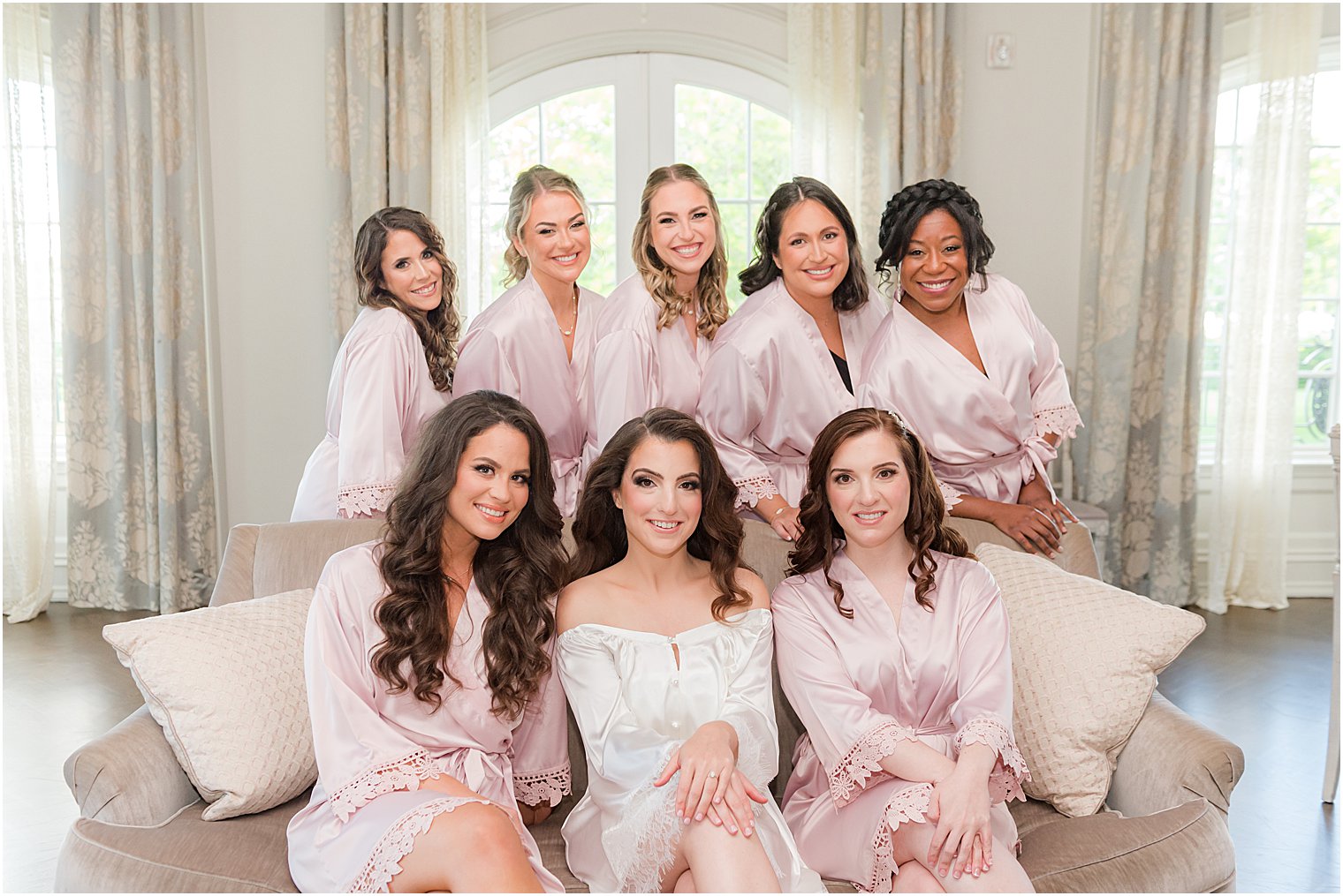 bride sits with bridesmaids in pink robes before summer Park Chateau Estate wedding
