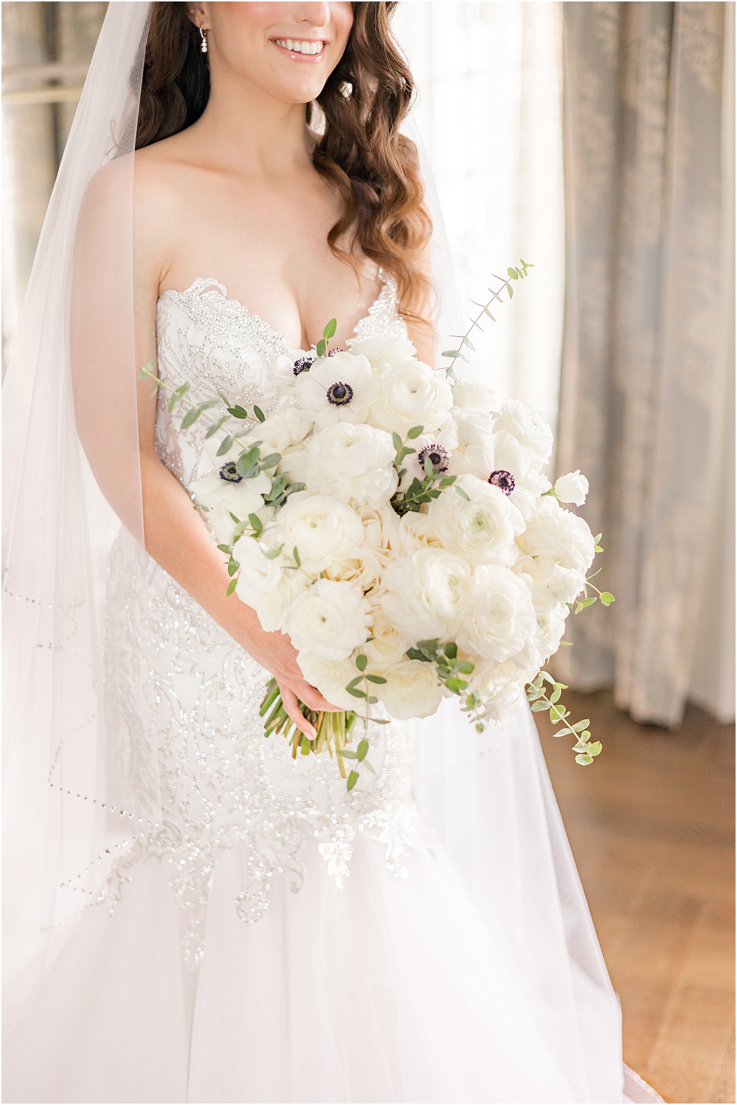 bride stands holding bouquet of white flowers