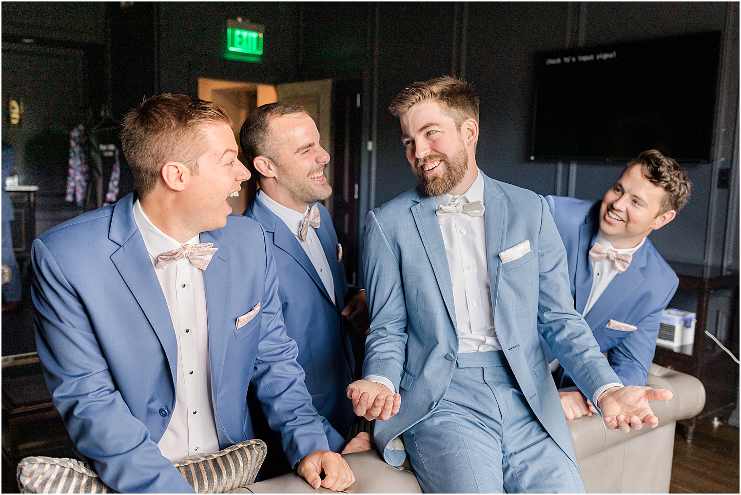 groom laughs with groomsmen in blue jackets