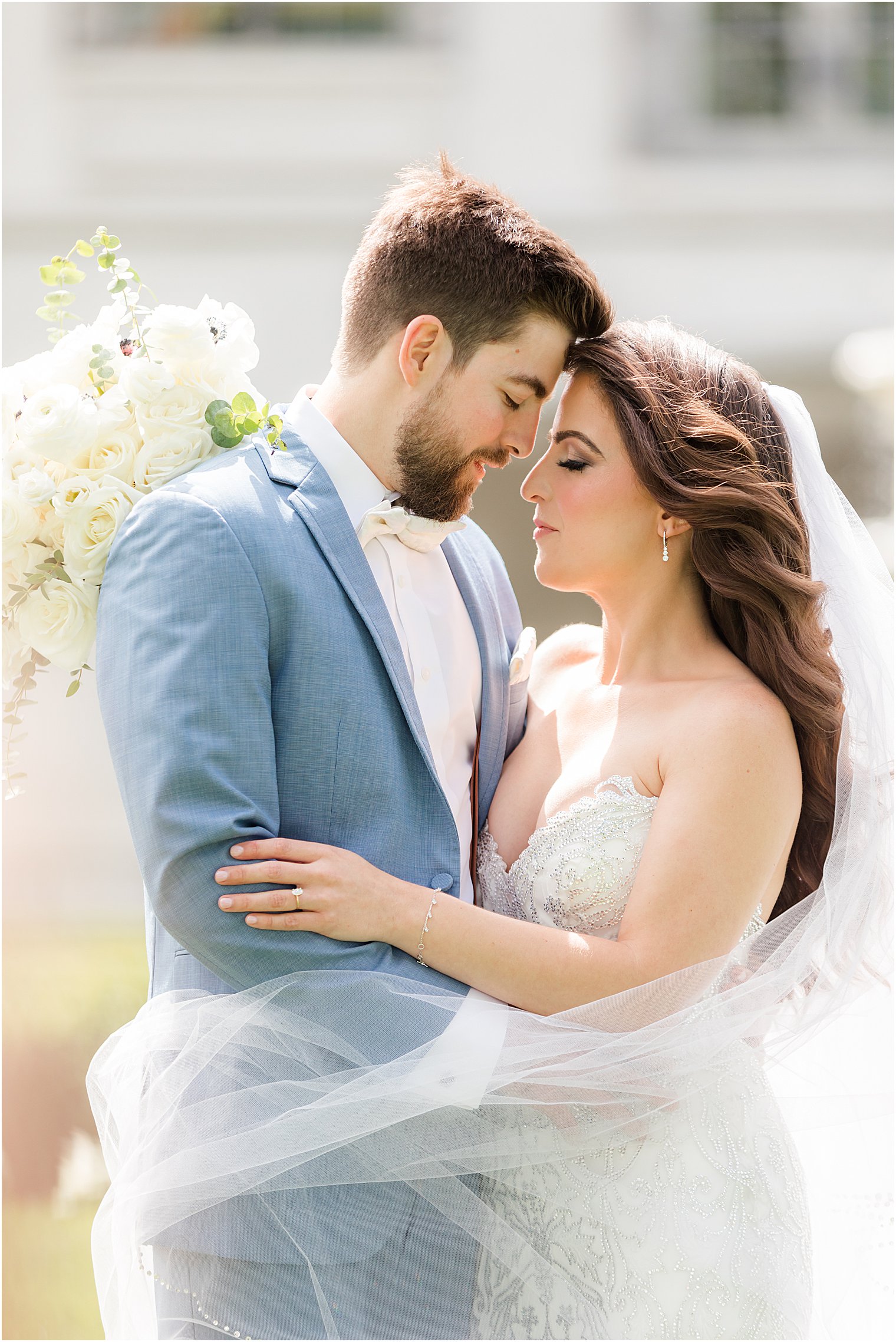 bride and groom hug with bride's veil around them during summer Park Chateau Estate wedding portraits