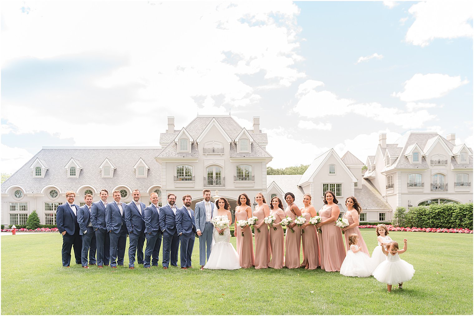 bride and groom stand with wedding party in blue and peach