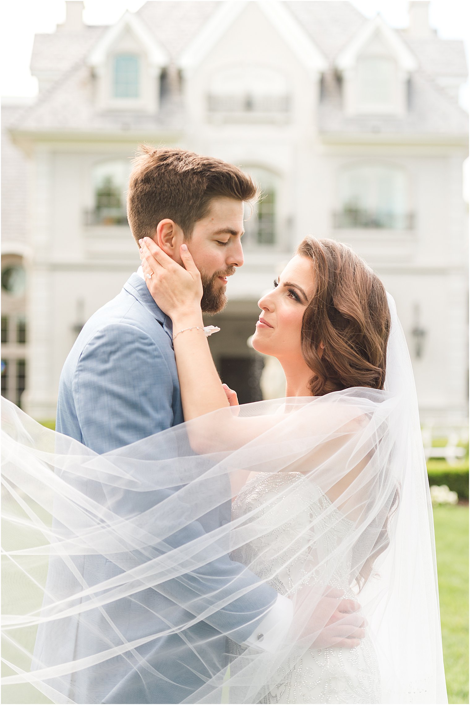 bride looks up at groom holding his cheek during summer wedding photos at Park Chateau Estate