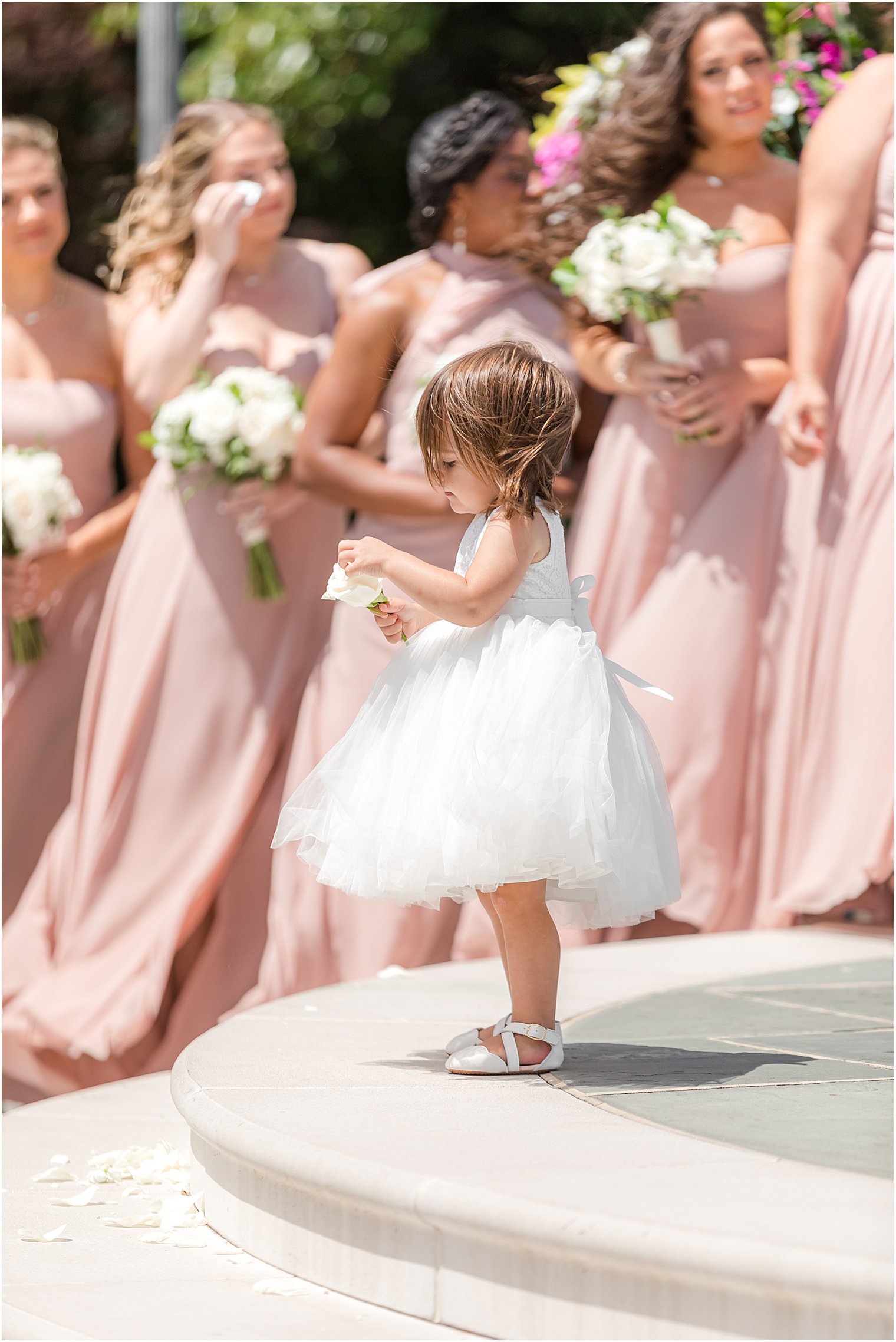 flower girl stands by bridesmaids during outdoor ceremony