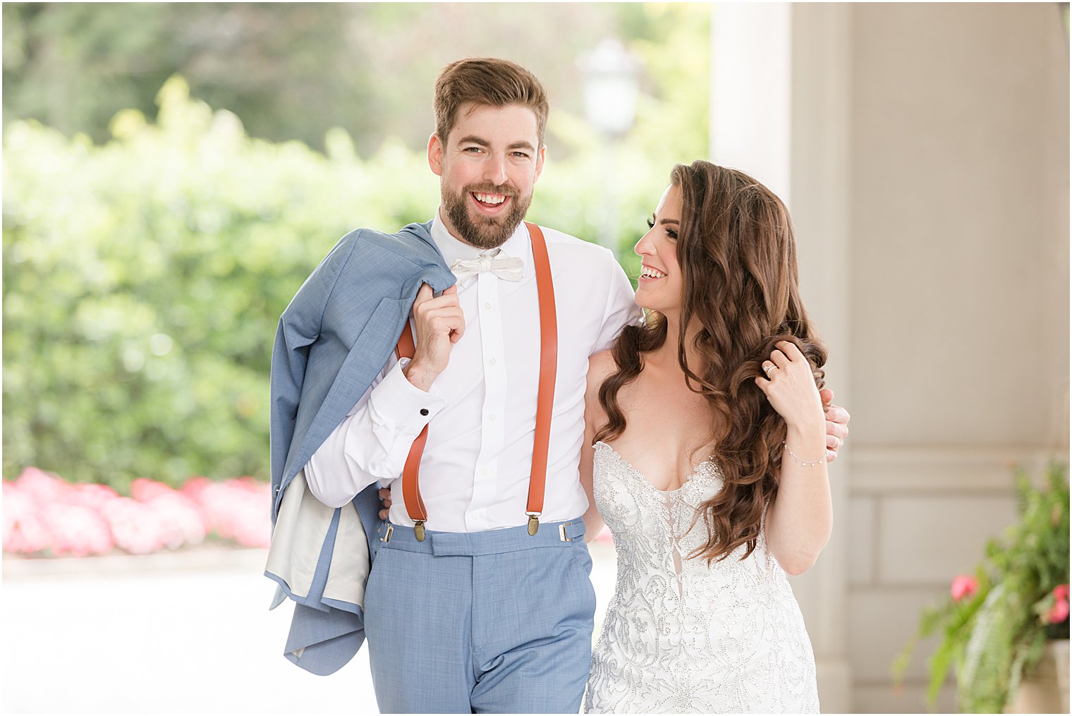 groom holds jacket over shoulder while hugging bride