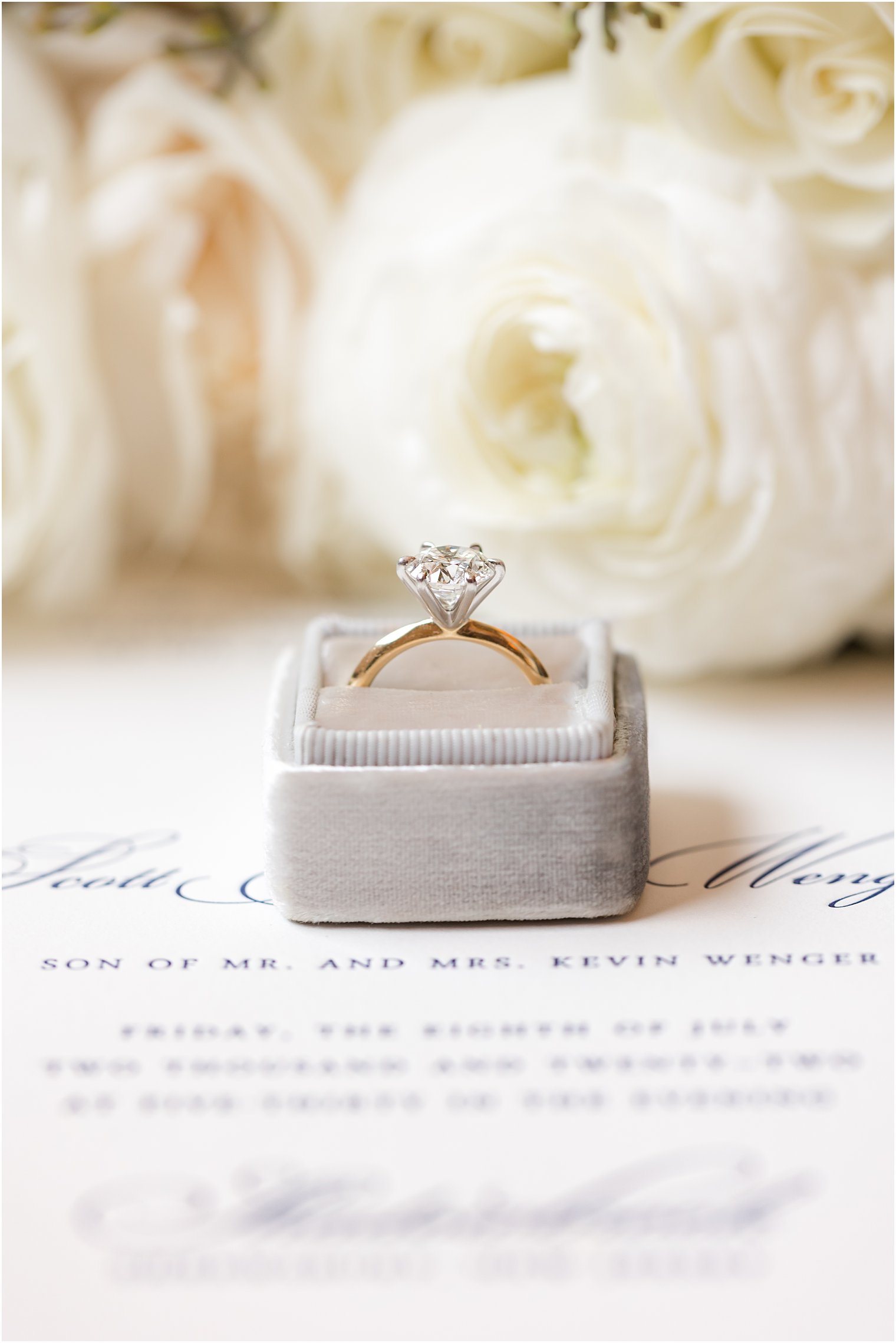 diamond ring rests in grey box by ivory flowers