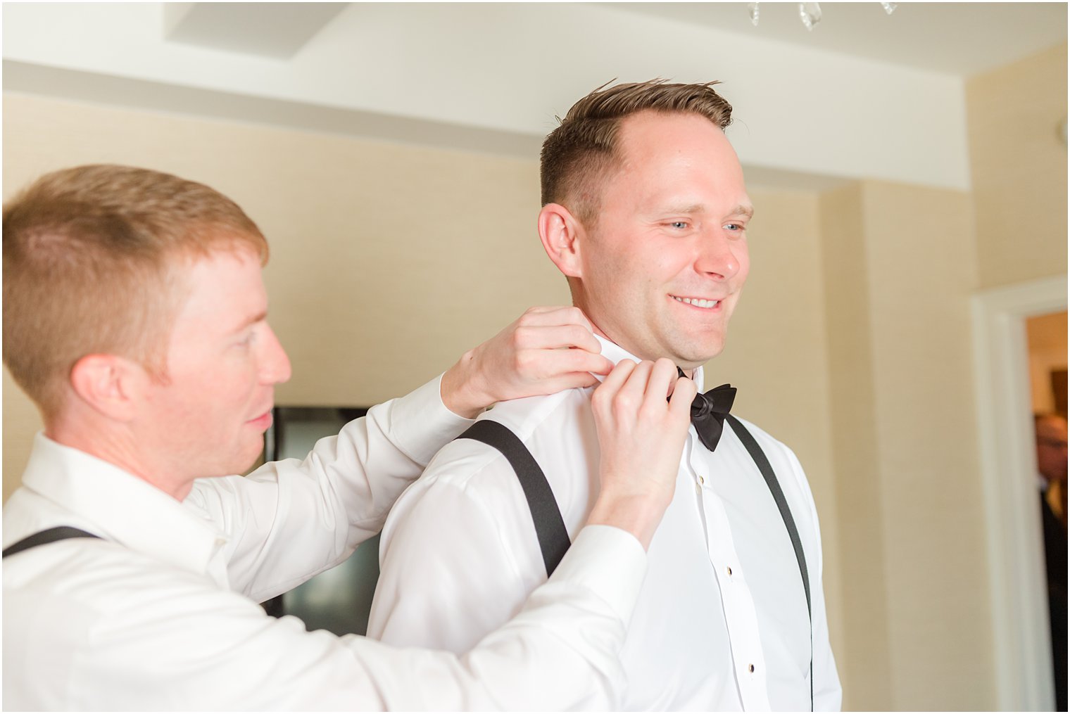 groomsman helps groom with tie before wedding at 