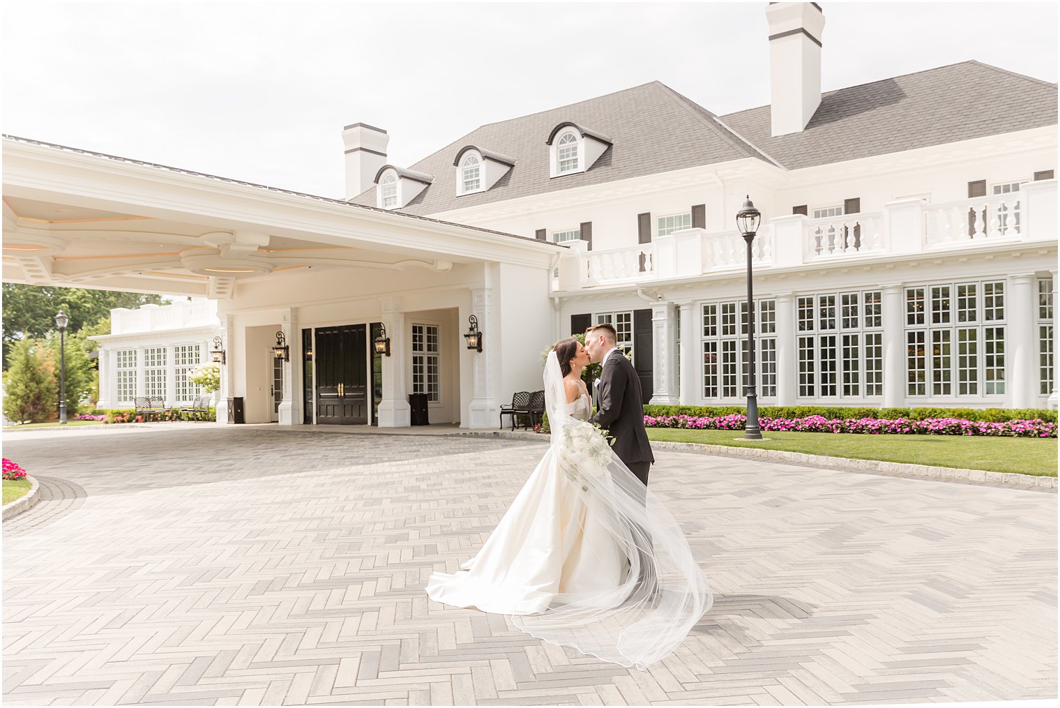 newlyweds kiss outside Shadowbrook at Shrewsbury with bride's veil around them