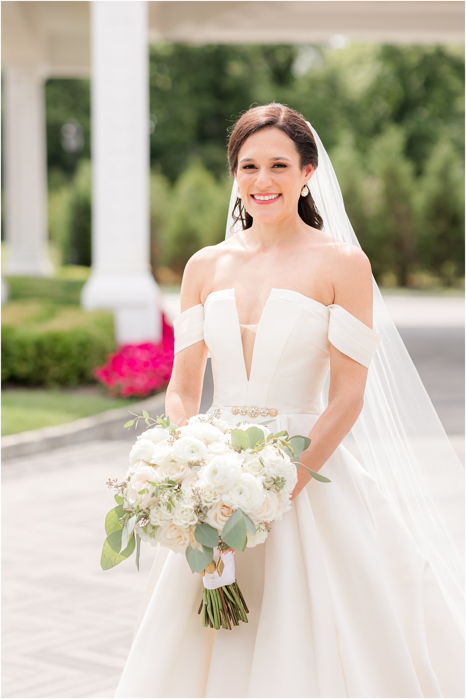 bride stands holding bouquet of ivory and pale pink flowers at Shadowbrook at Shrewsbury