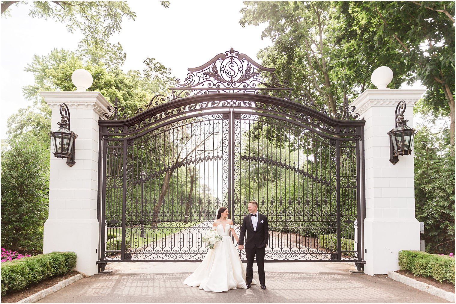 newlyweds pose outside wrought iron gates at Shadowbrook at Shrewsbury