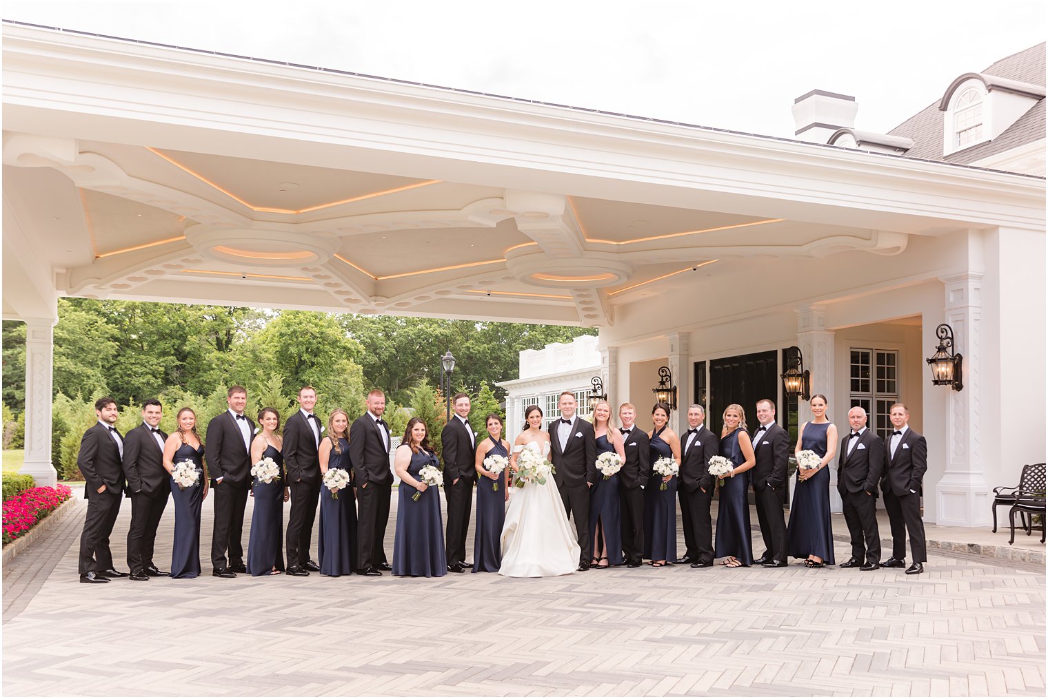 newlyweds stand with wedding party outside Shadowbrook at Shrewsbury