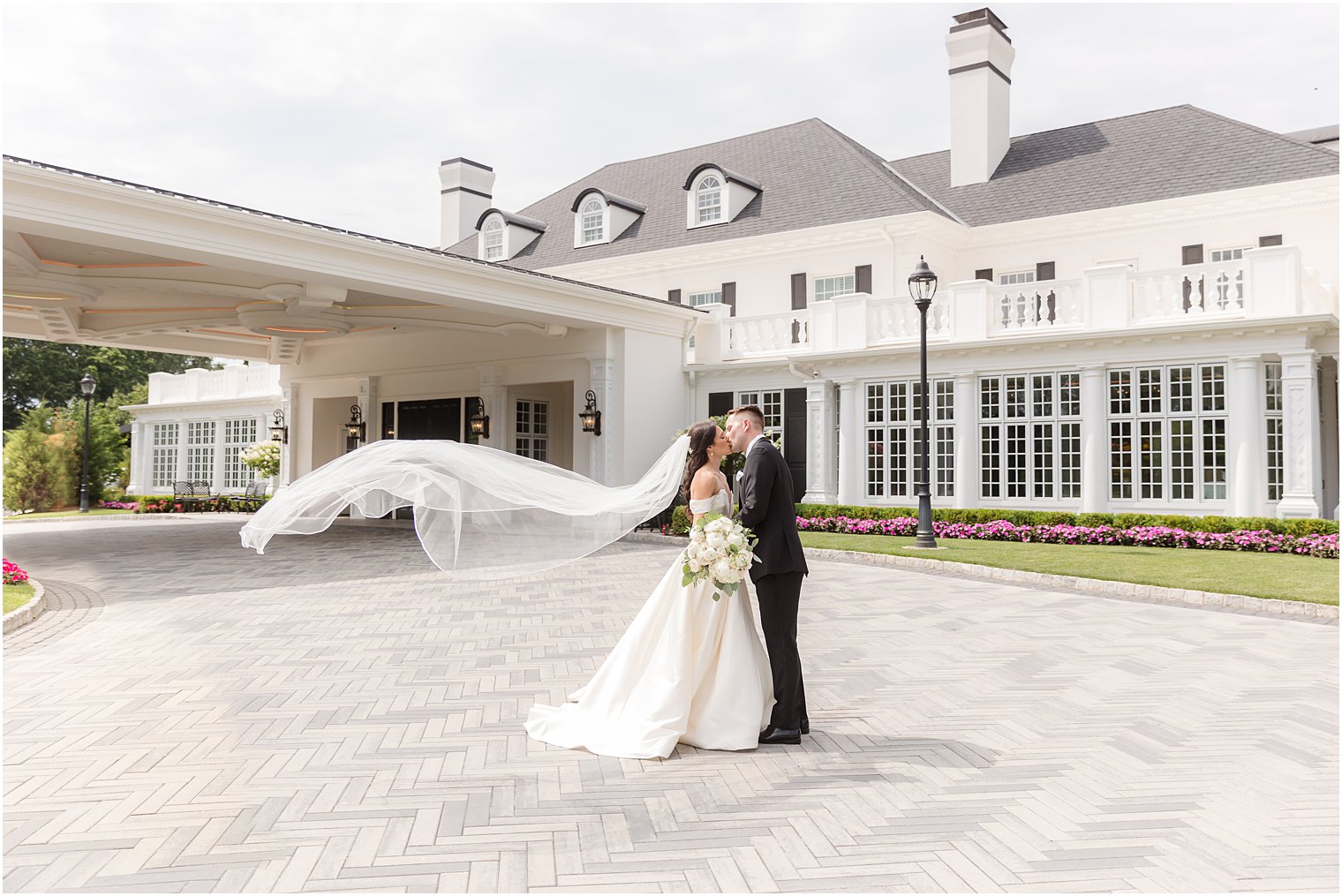 newlyweds kiss outside Shadowbrook at Shrewsbury with bride's veil floating 