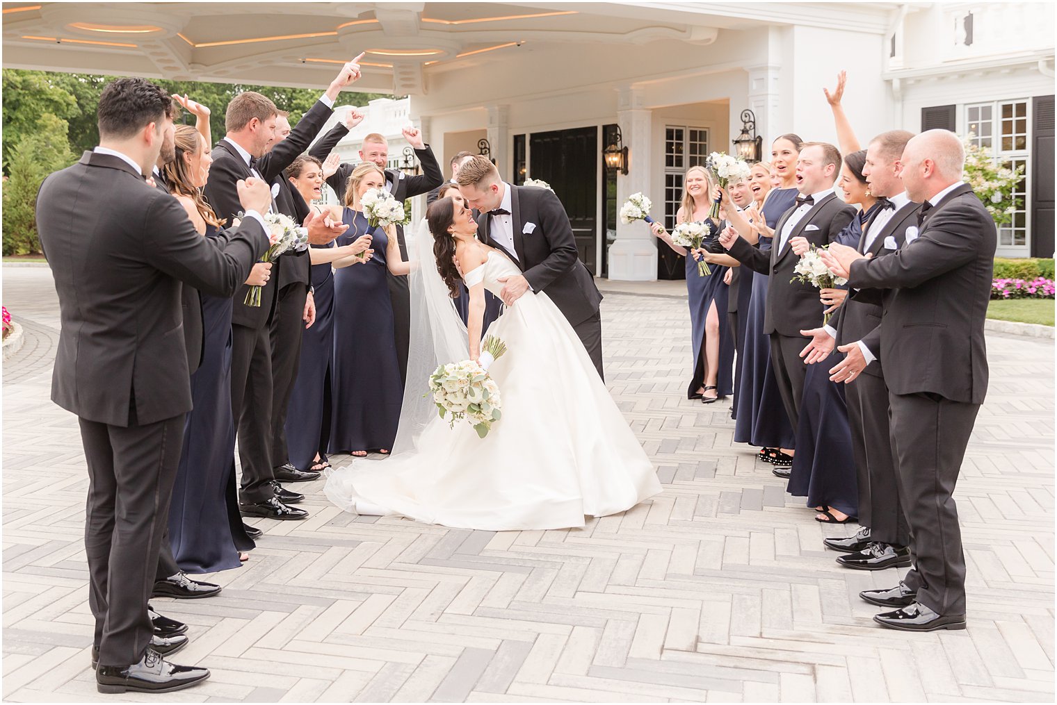 groom dips bride during kiss in front of wedding party