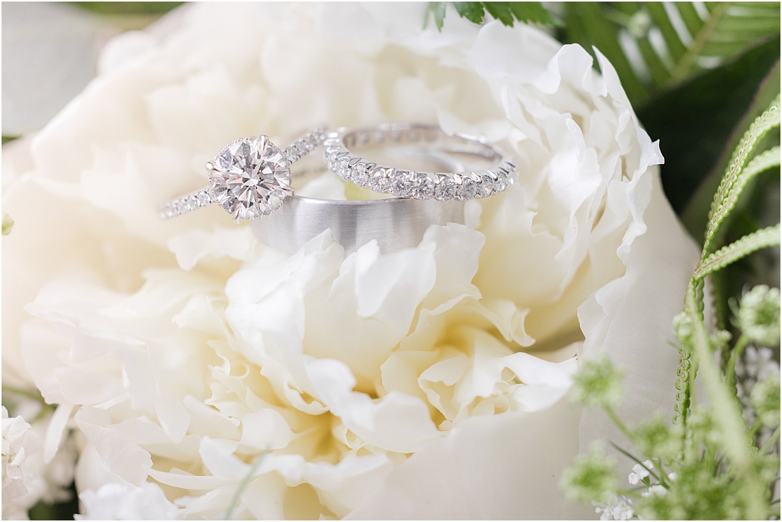 bride's wedding rings rest on ivory peony 