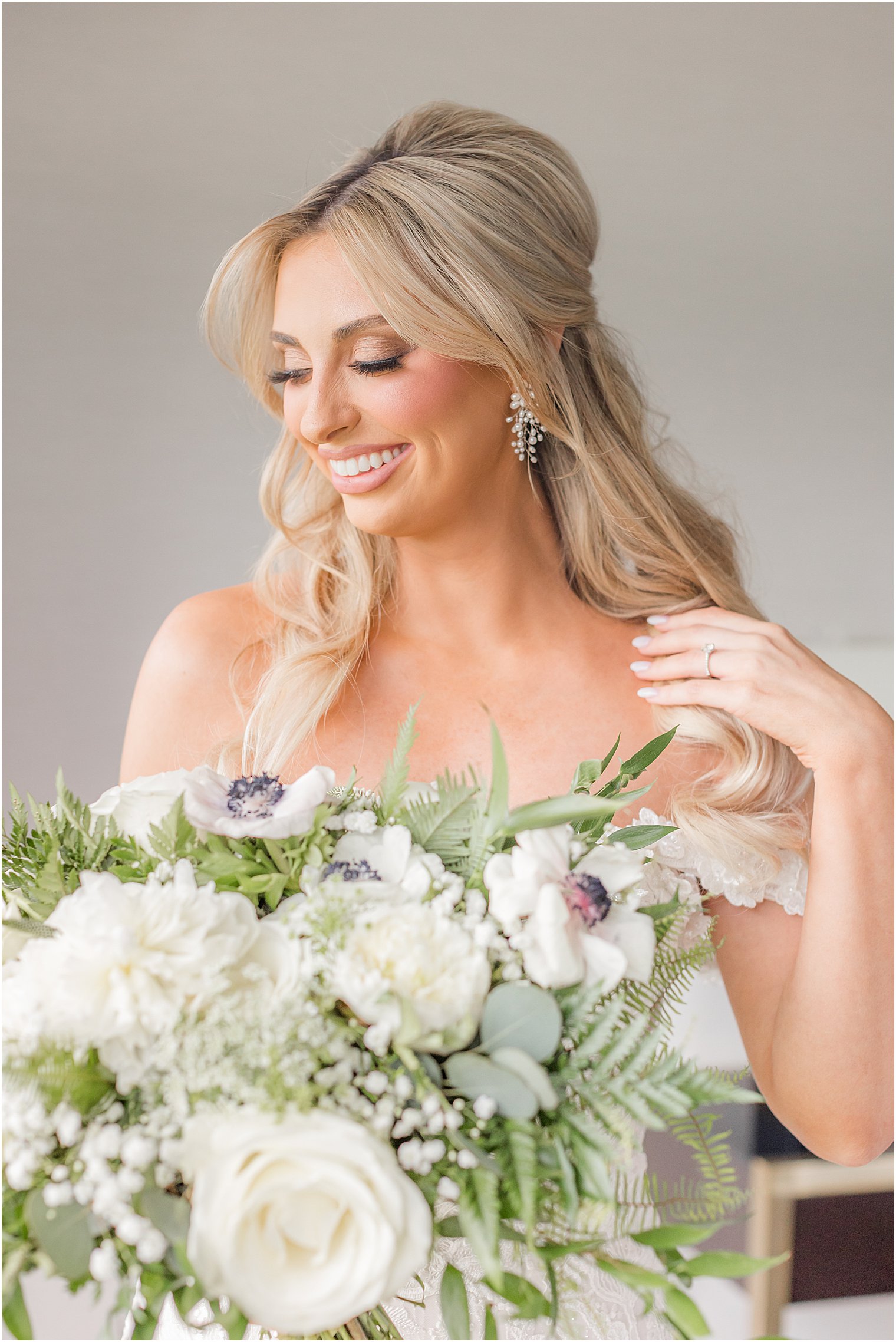 bride holds bouquet and pulls hair over shoulder during prep for The English Manor wedding