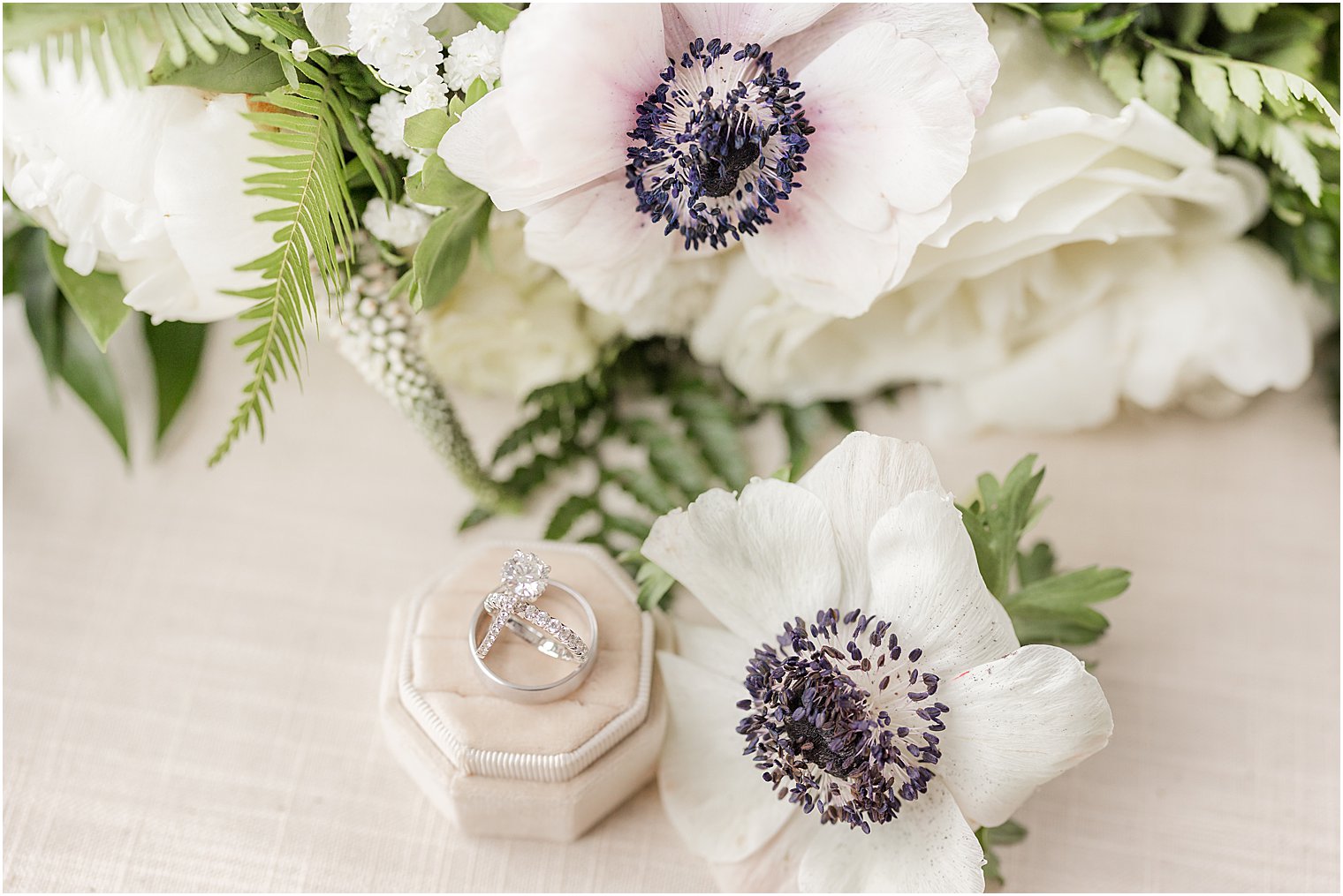 bride's rings rest in tan box by white bouquet 