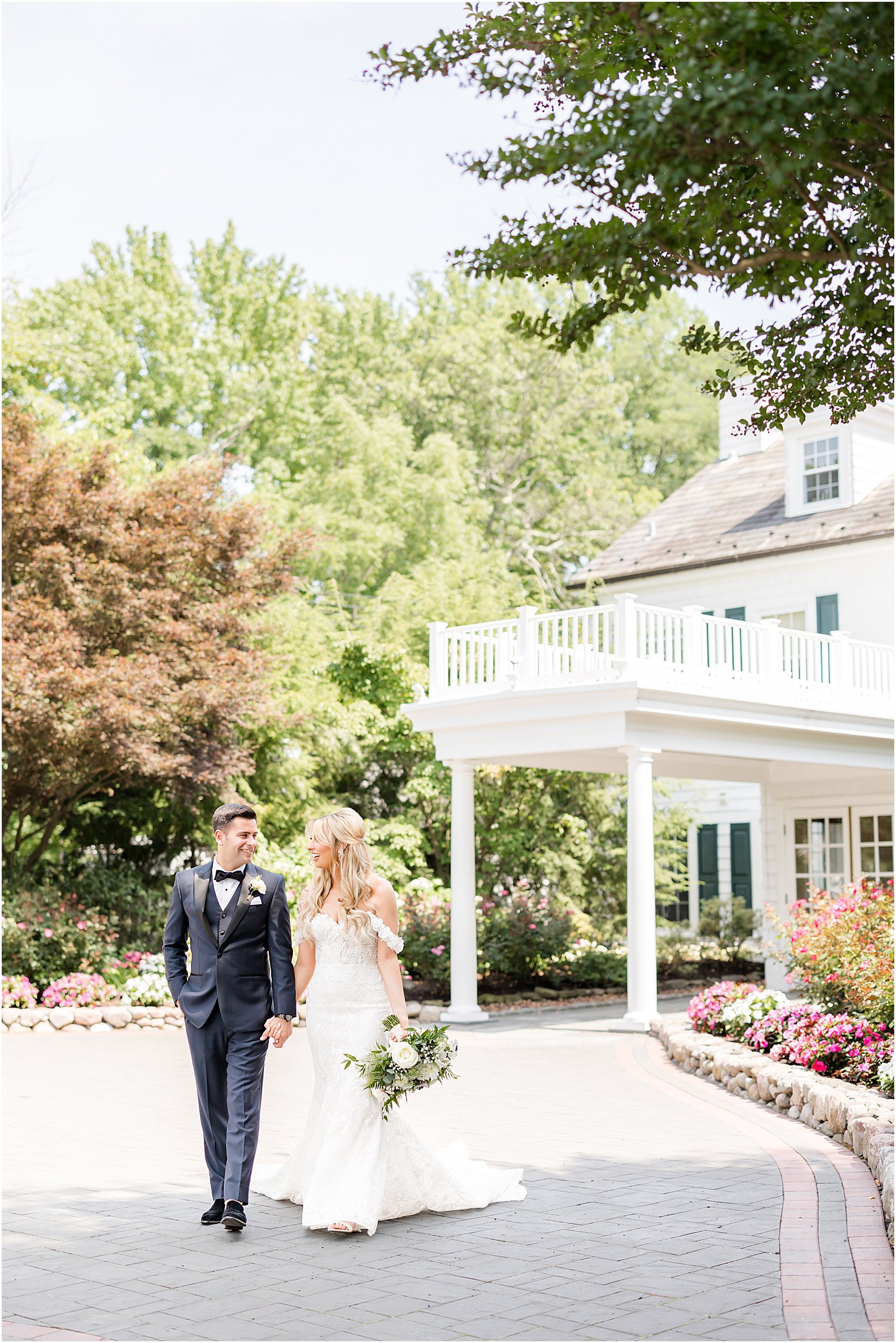 bride and groom hold hands walking outside The English Manor