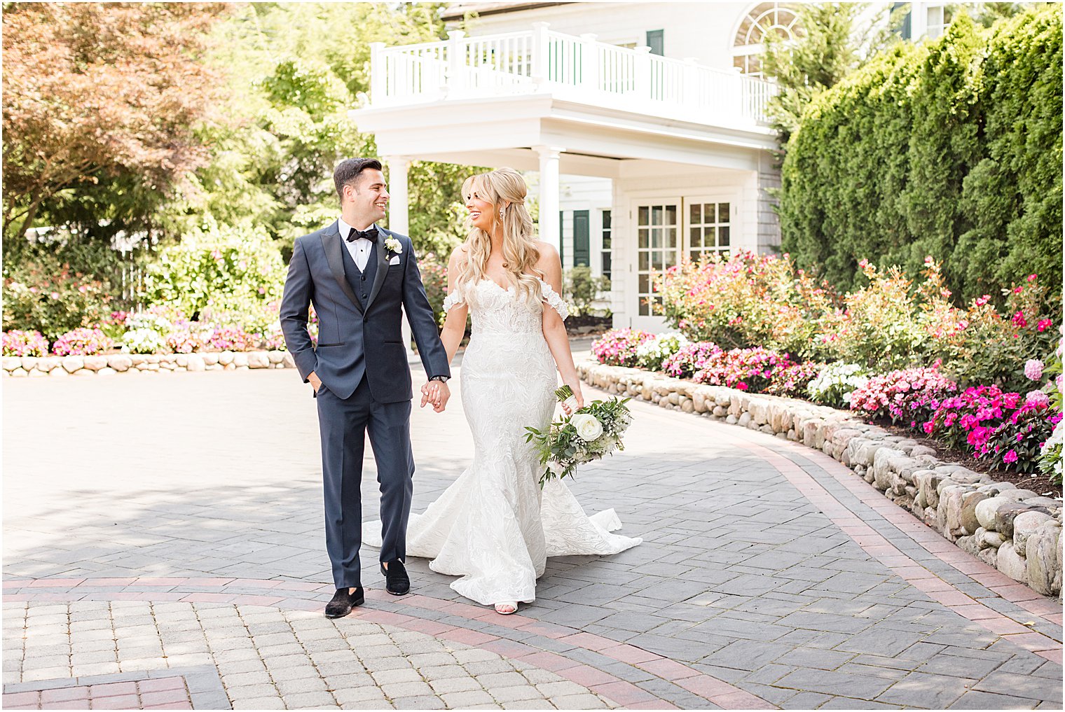 newlyweds hold hands walking in driveway of The English Manor