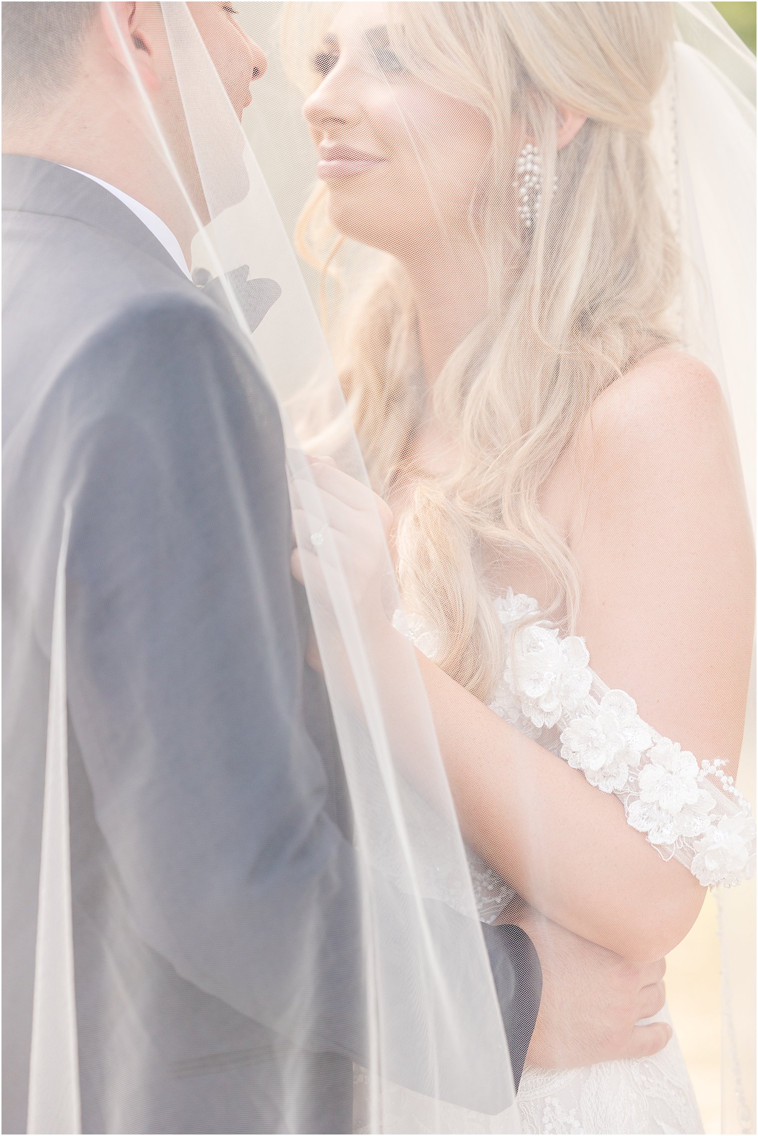 bride and groom smile together under veil