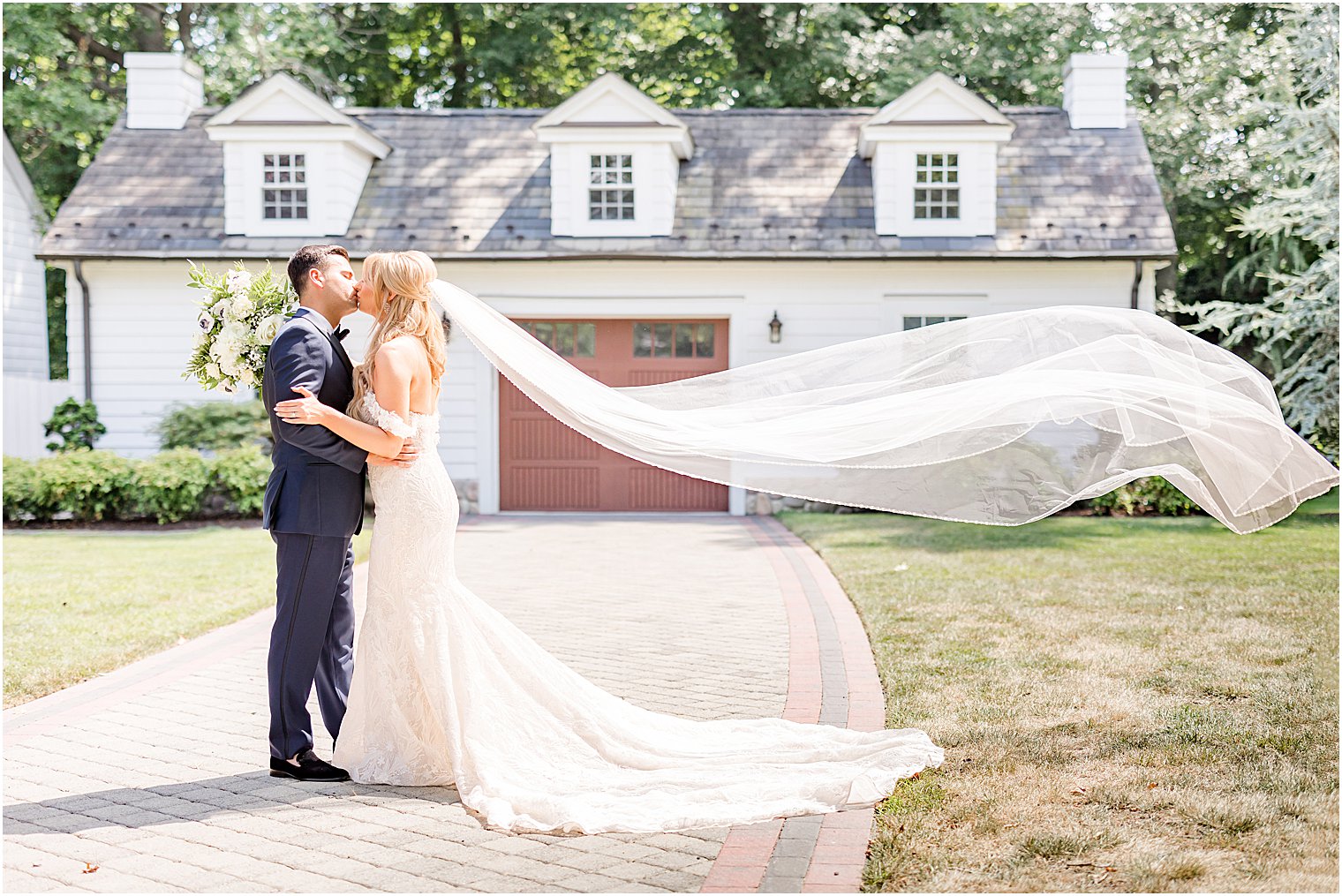 newlyweds kiss while bride's veil floats behind her