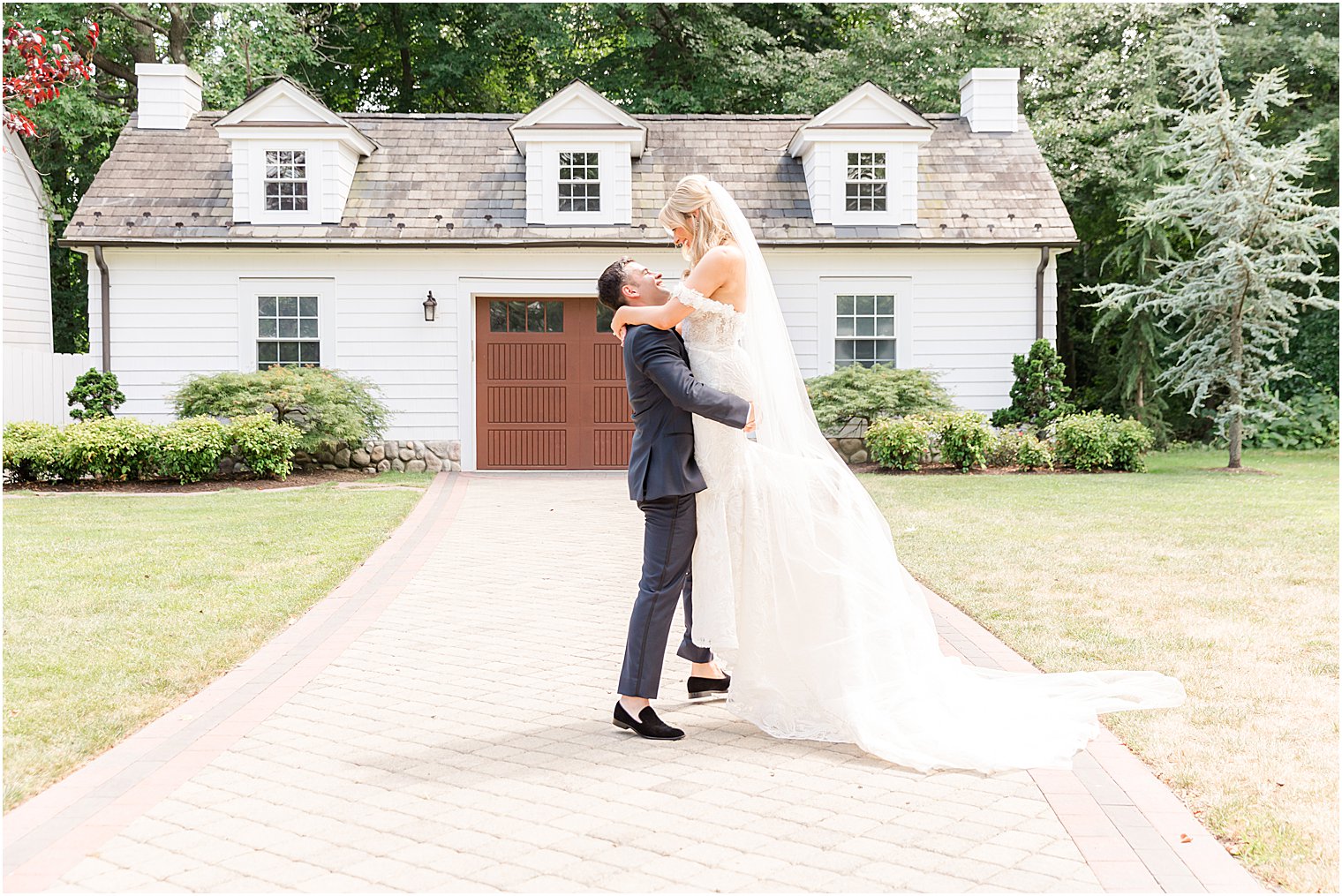 groom lifts bride up standing outside The English Manor