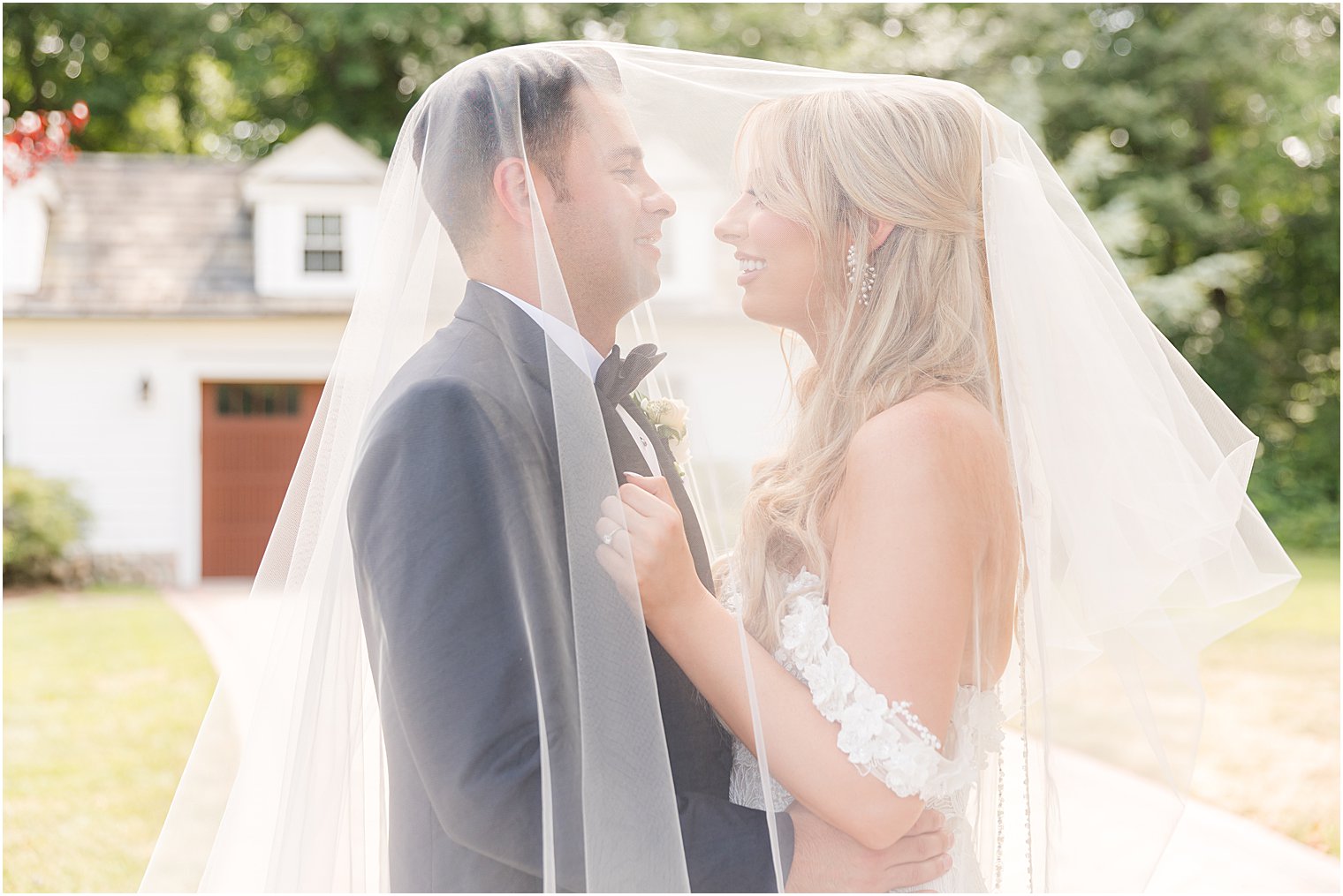 bride and groom smile under veil at each other 