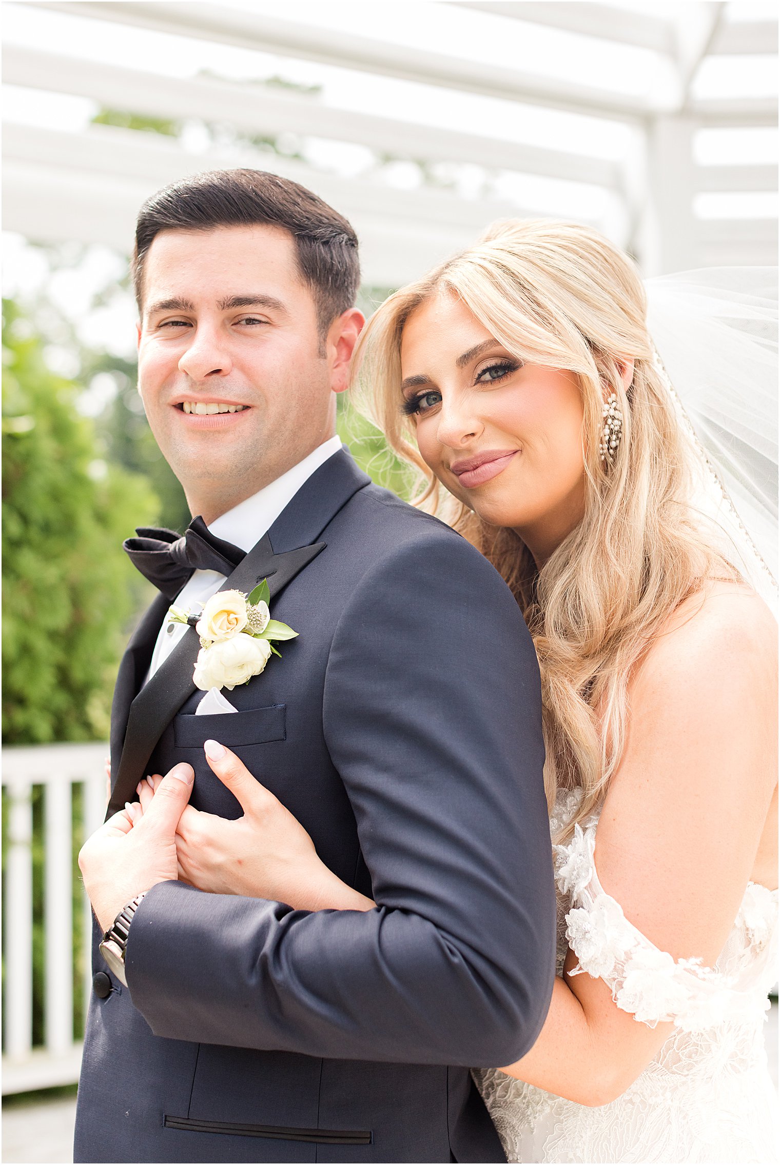 bride hugs groom leaning her head on his shoulder from behind 