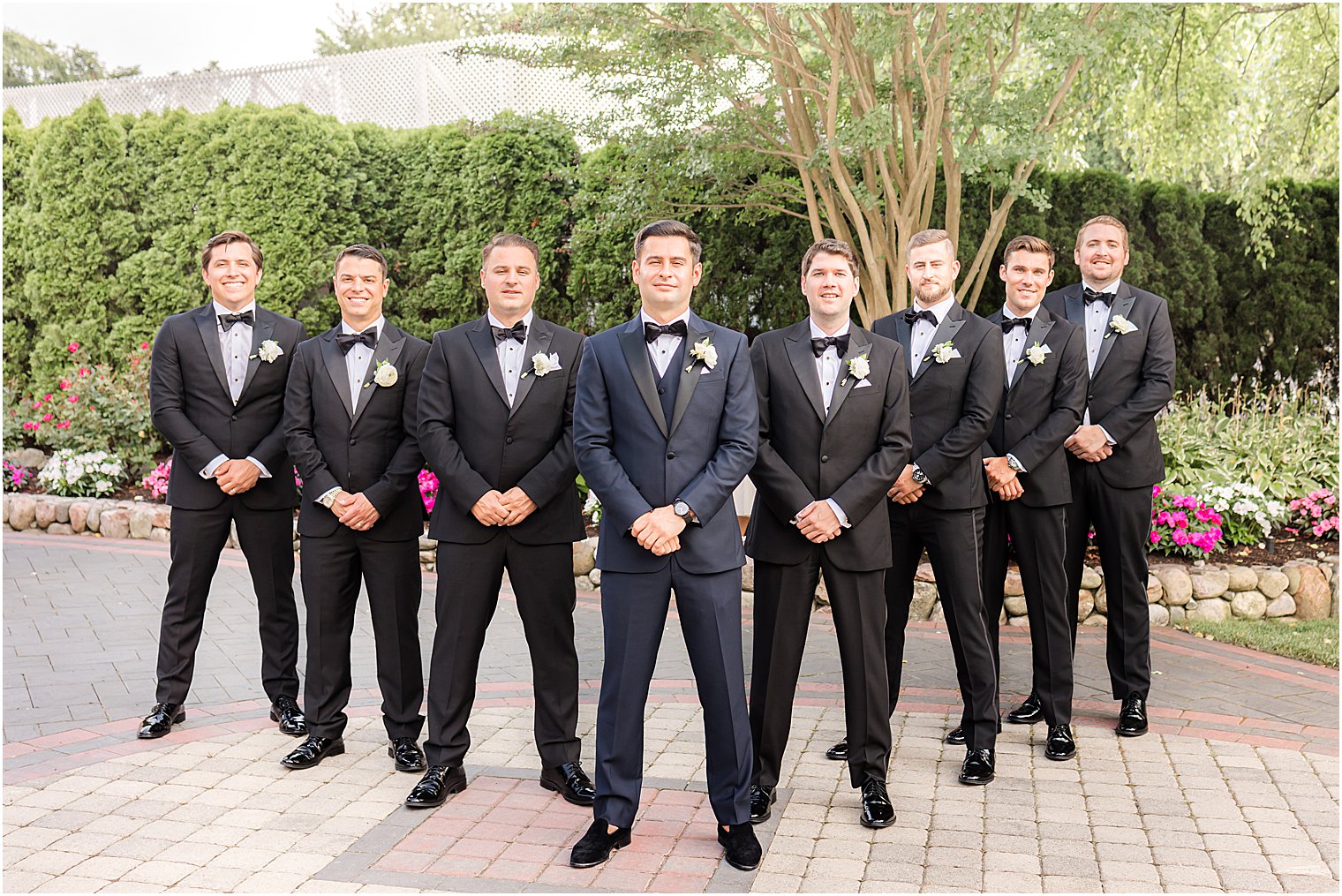 groom stands with groomsmen in black suits at The English Manor