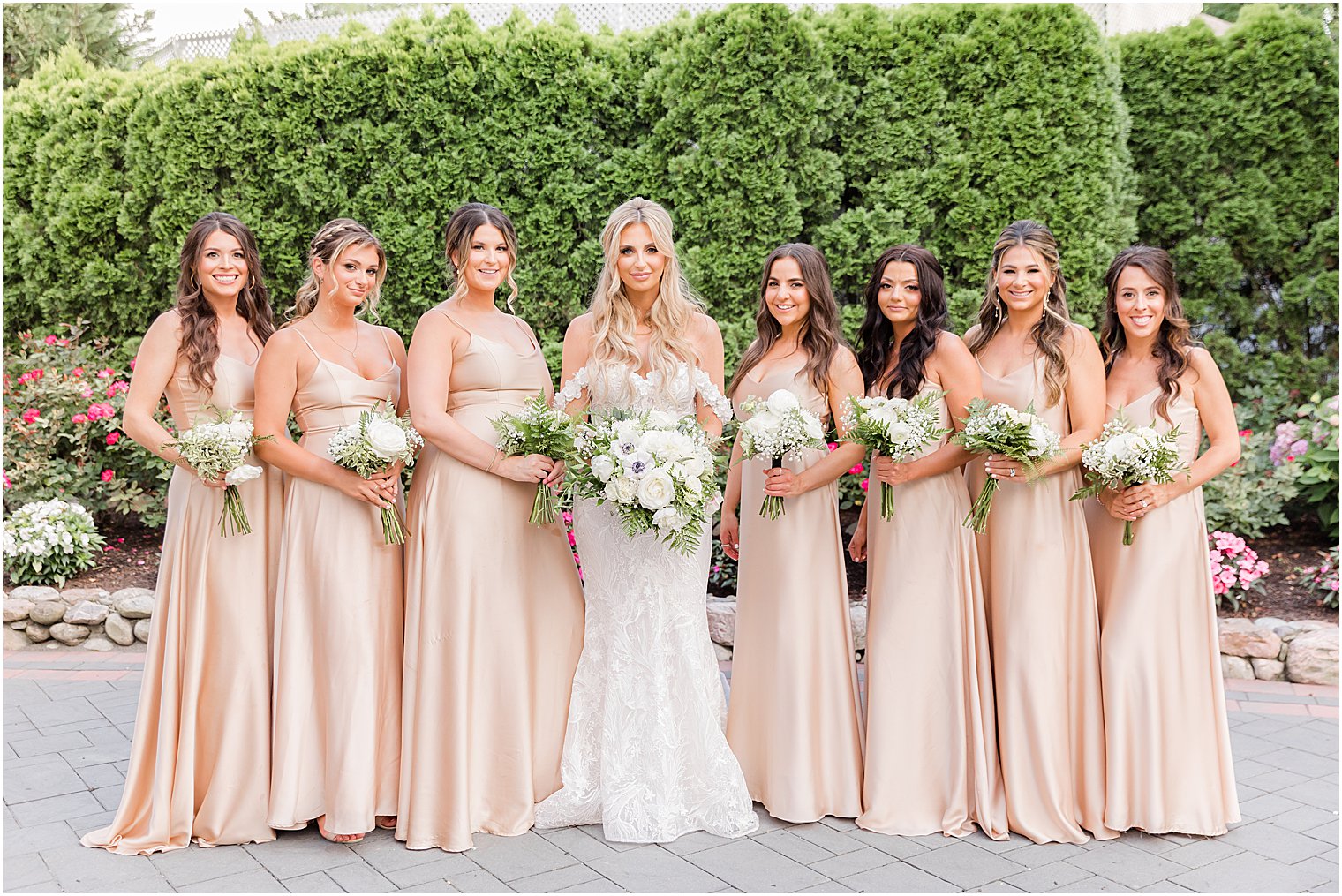 bride poses with bridesmaids in champagne gowns