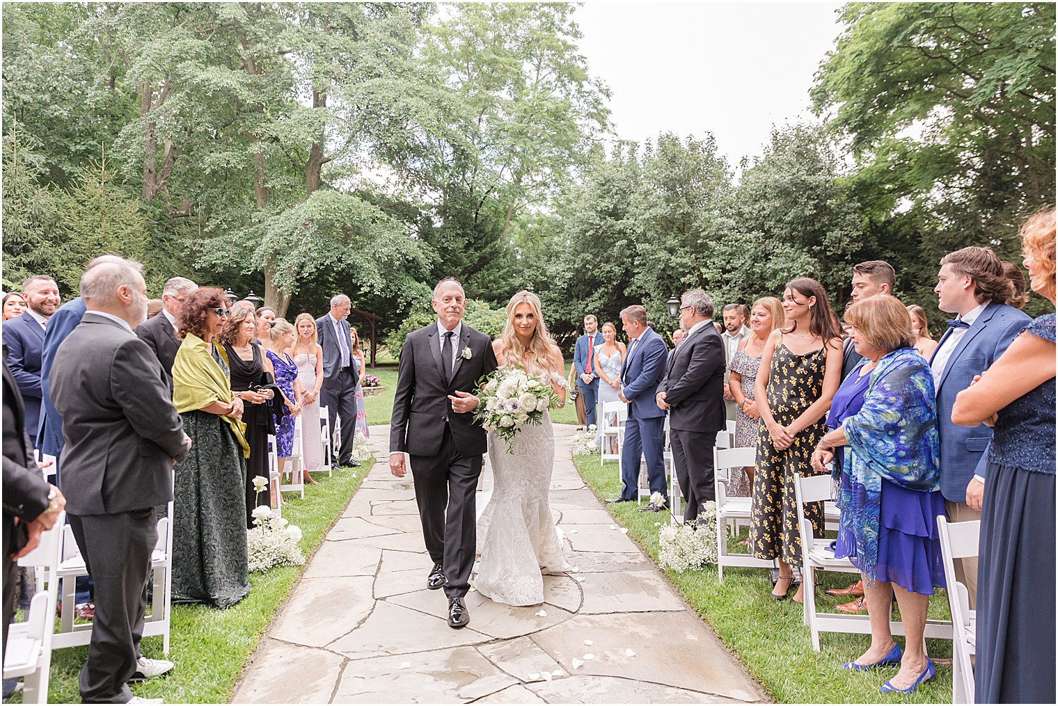 bride and dad walk down aisle for Jewish ceremony in the gardens of The English Manor
