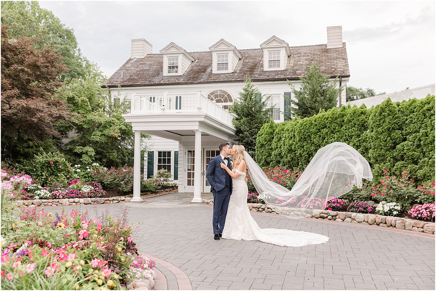 newlyweds kiss while bride's veil floats behind her