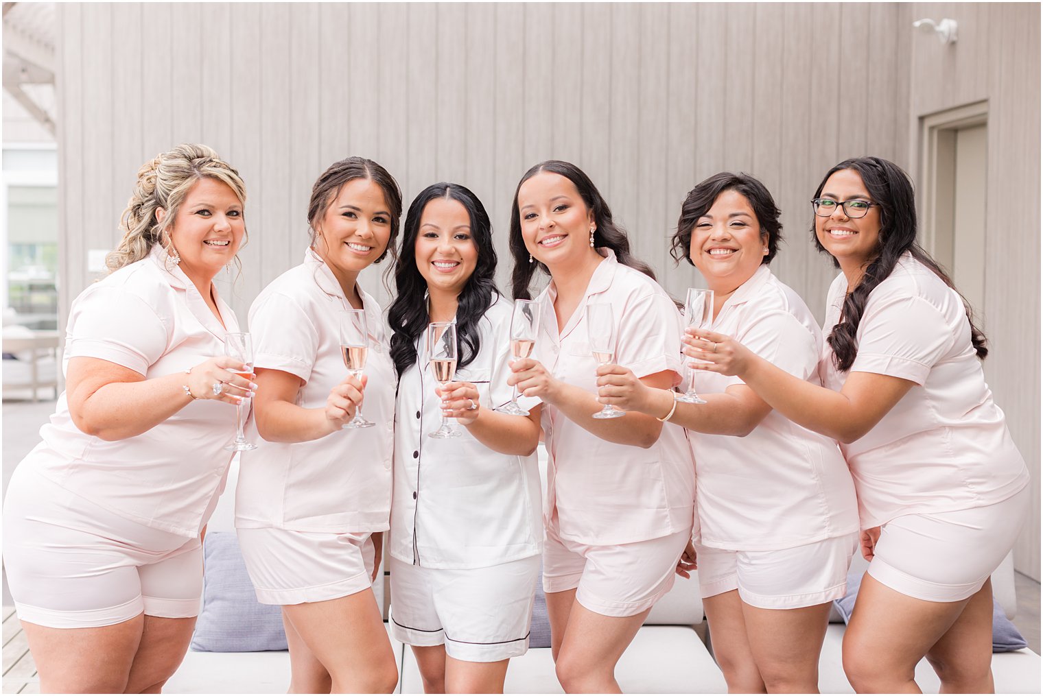bridesmaids hug bride with champagne glasses 