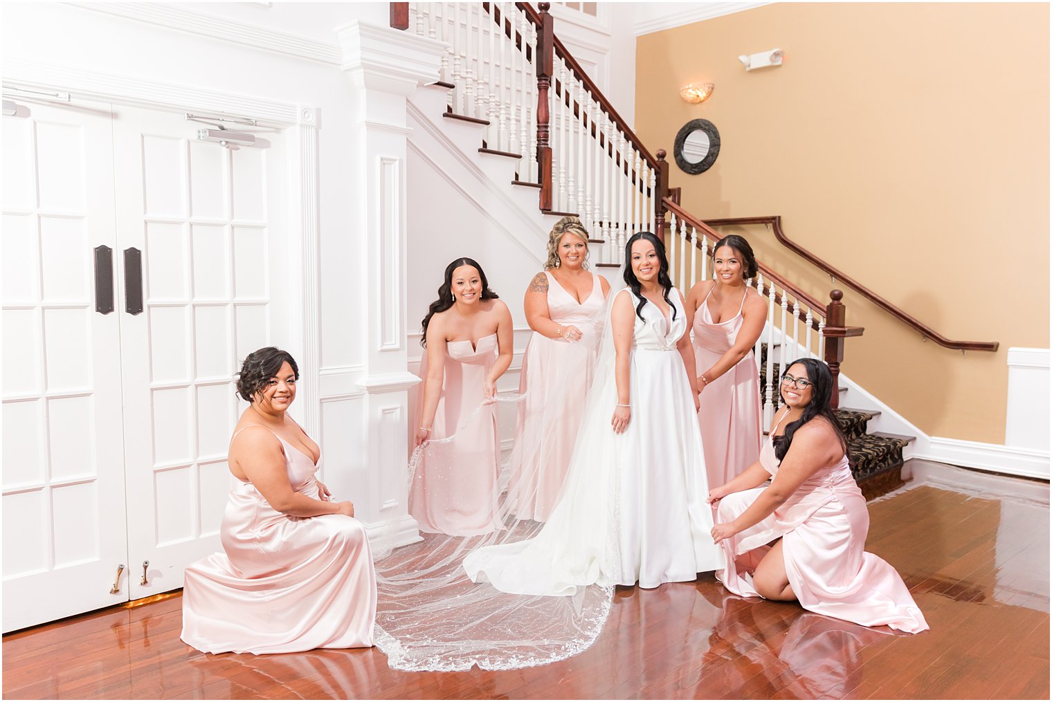 bridesmaids help bride with veil and wedding gown