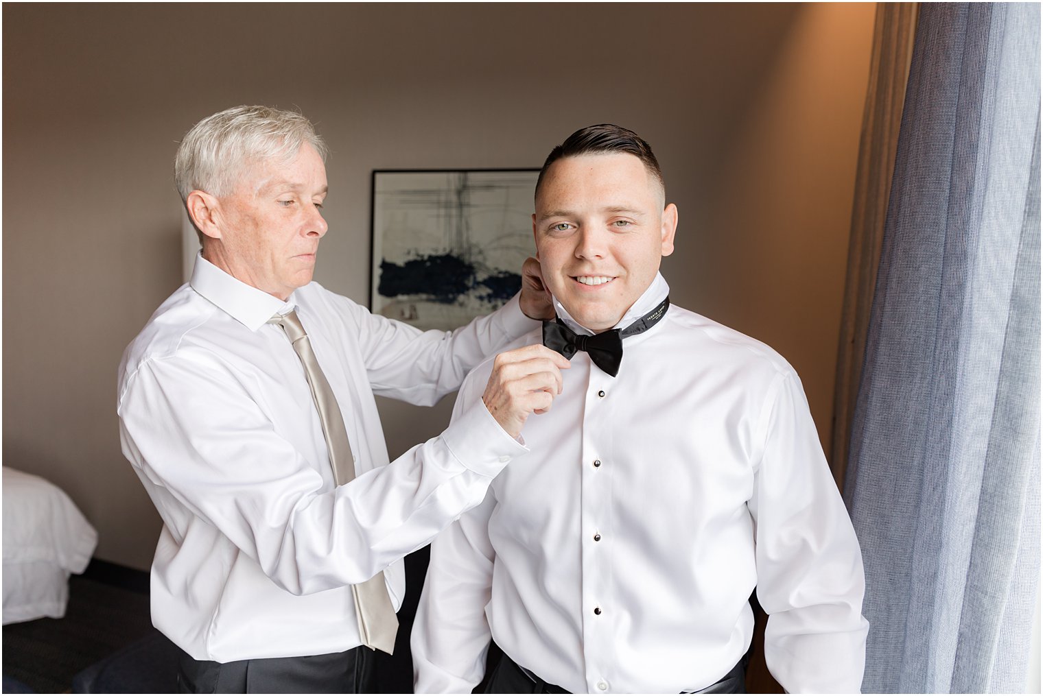 father helps groom with bowtie before Hamilton Manor wedding