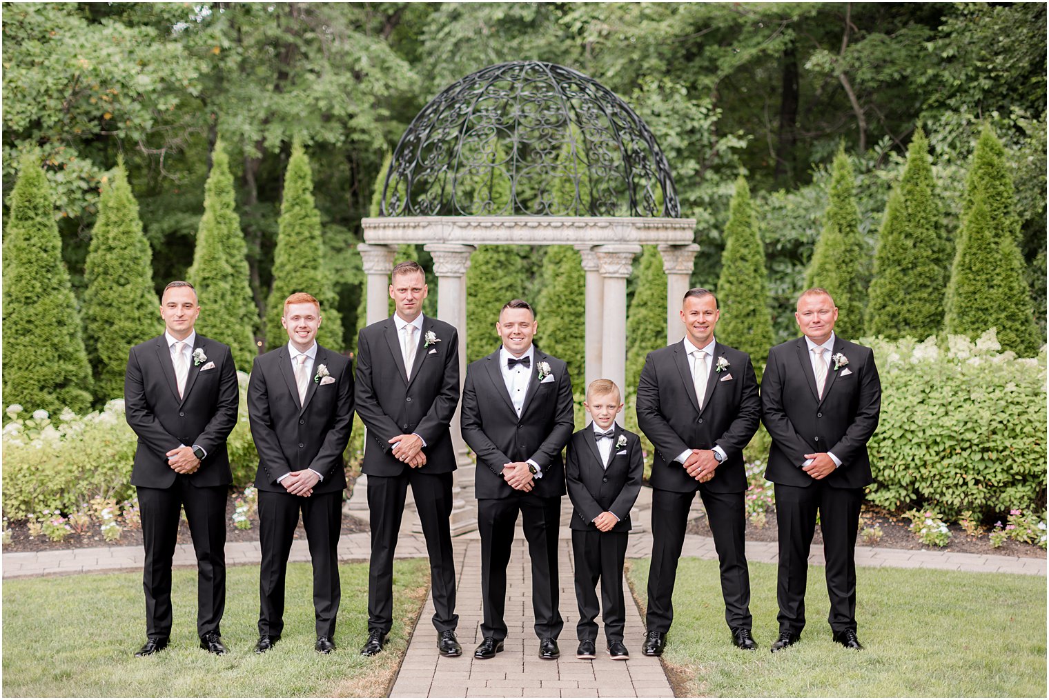 groom stands with groomsmen in classic black tuxes at Hamilton Manor