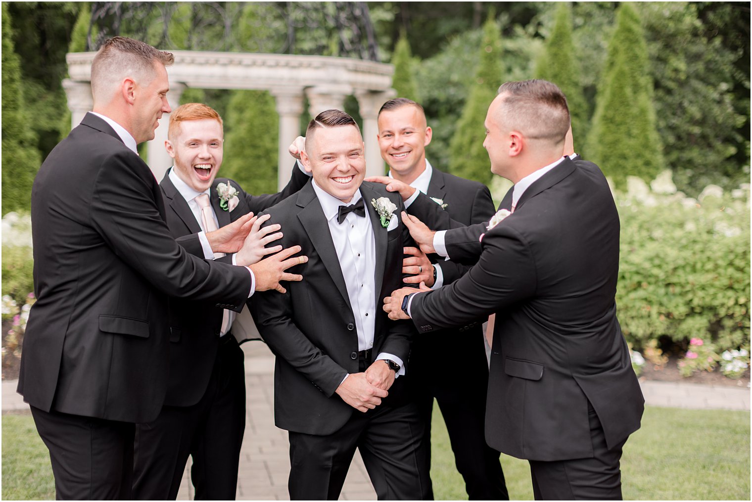 groomsmen laugh with groom in black tux