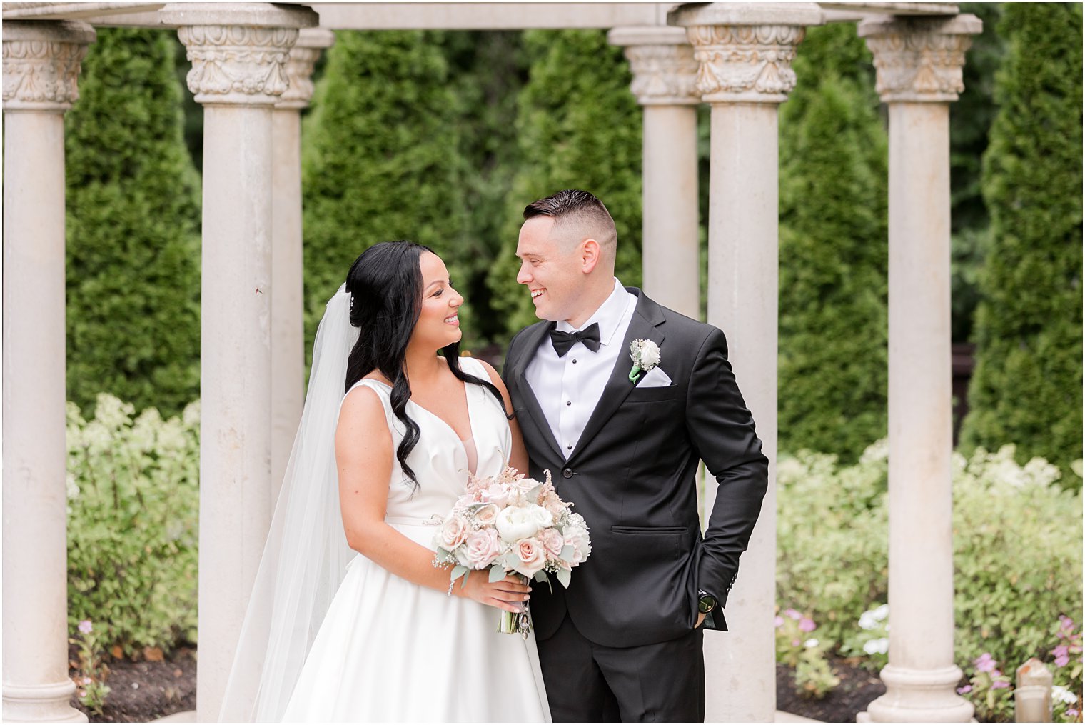 groom smiles at bride by gazebo