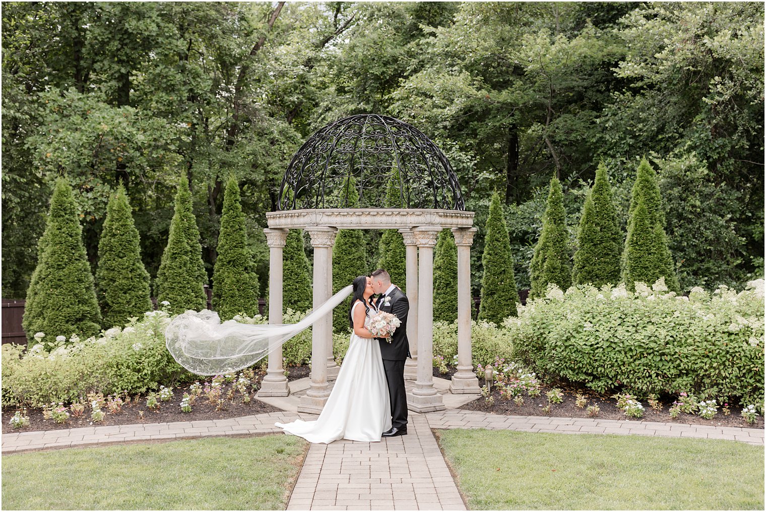 bride and groom kiss by gazebo with wrought iron top
