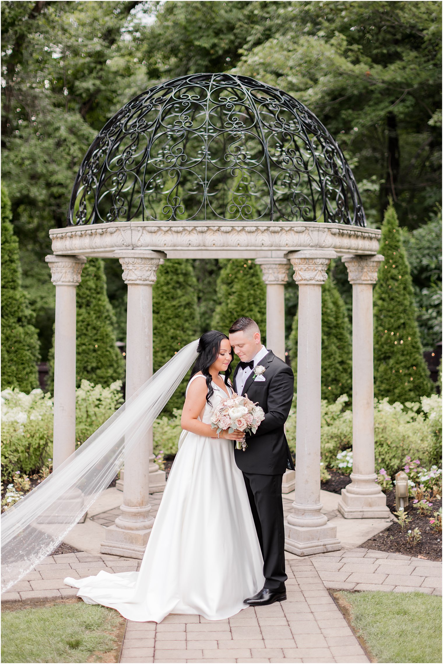 newlyweds hug by Hamilton Manor gazebo in garden 