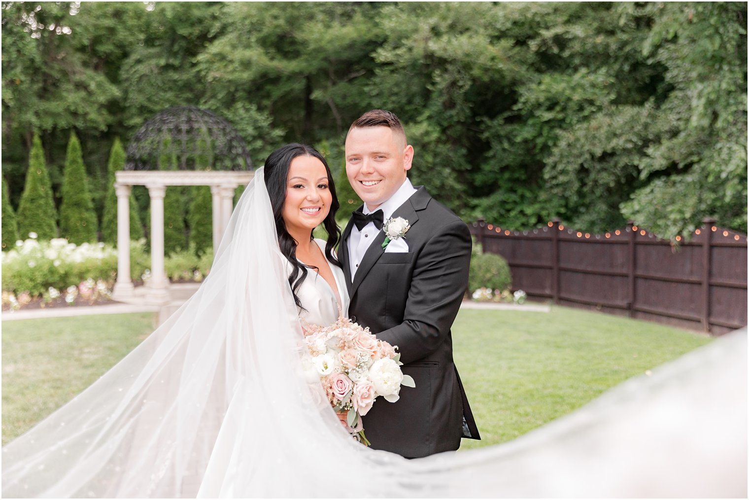 bride and groom hug with bride's veil draped around them at Hamilton Manor