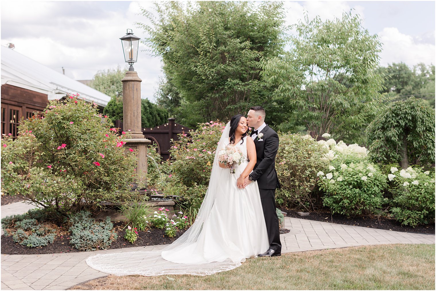 groom hugs bride from behind holding hand in gardens of Hamilton Manor