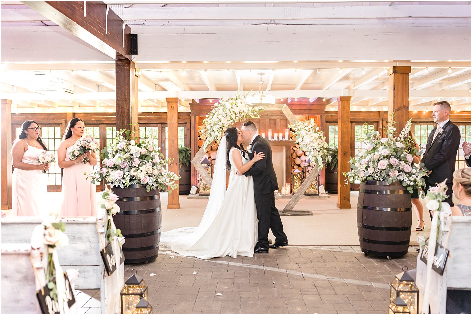 couple kisses by flower covered arch