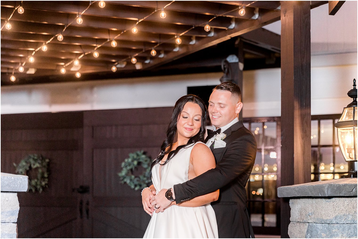 groom hugs bride from behind at night at Hamilton Manor