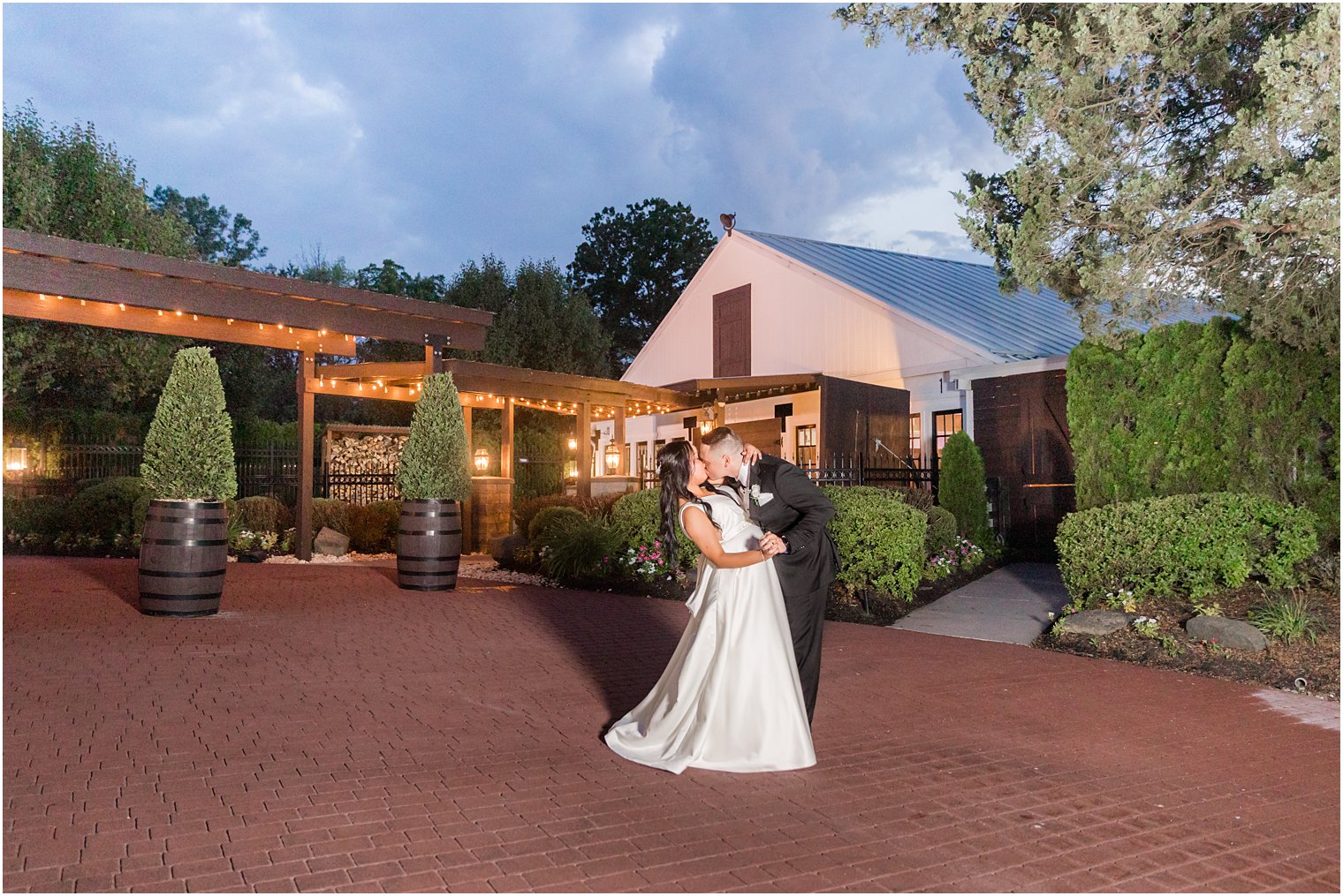 newlyweds kiss during nighttime wedding photos outside Hamilton Manor