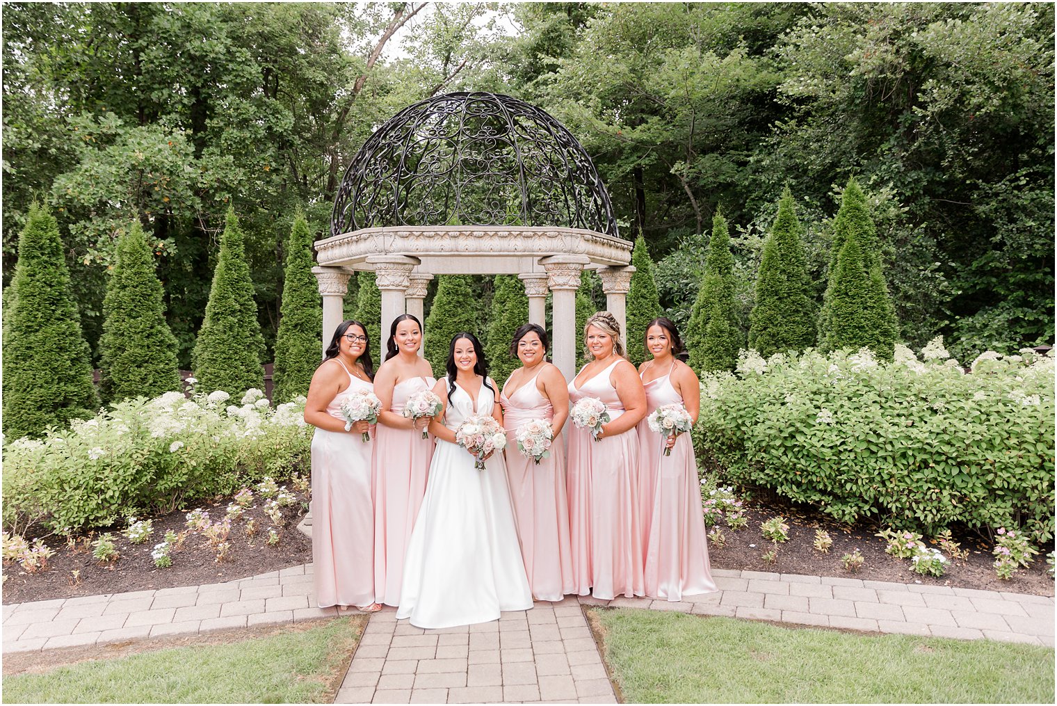 bride stands with bridesmaids in pink gowns outside Hamilton Manor
