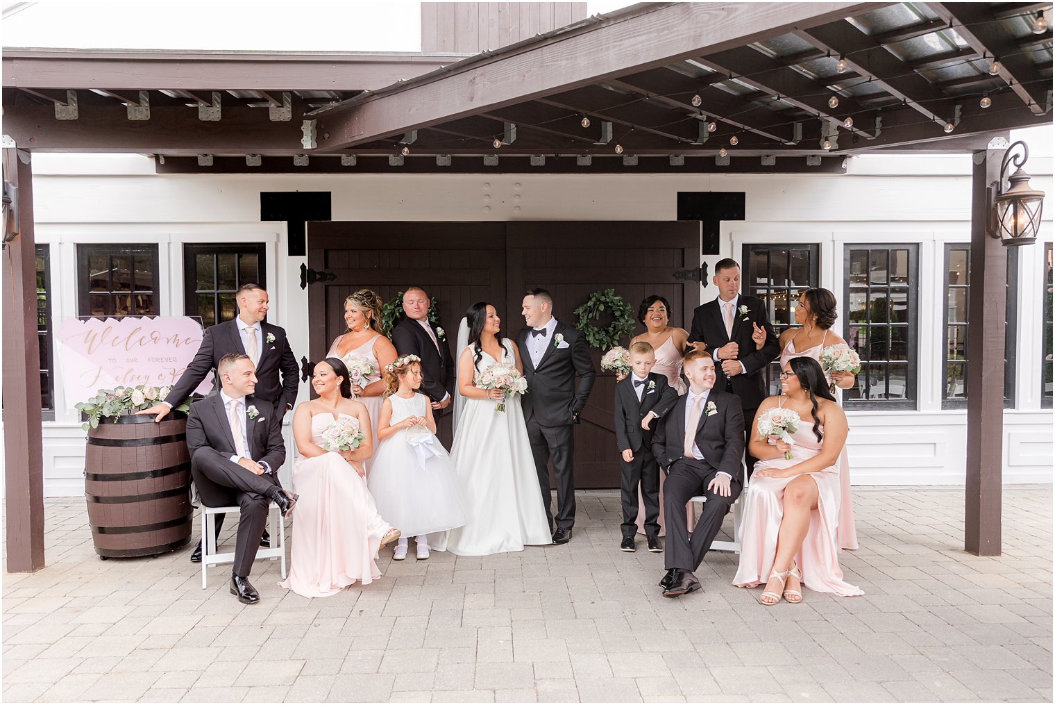 newlyweds pose under overhang at Hamilton Manor with wedding party
