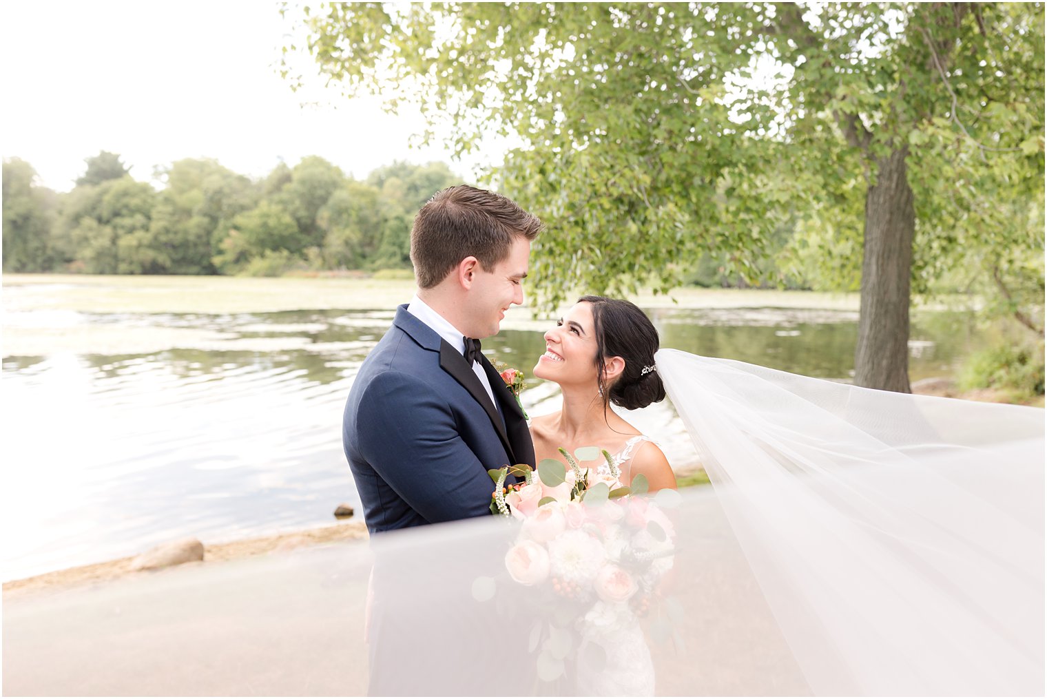 bride smiles up at groom with veil around them