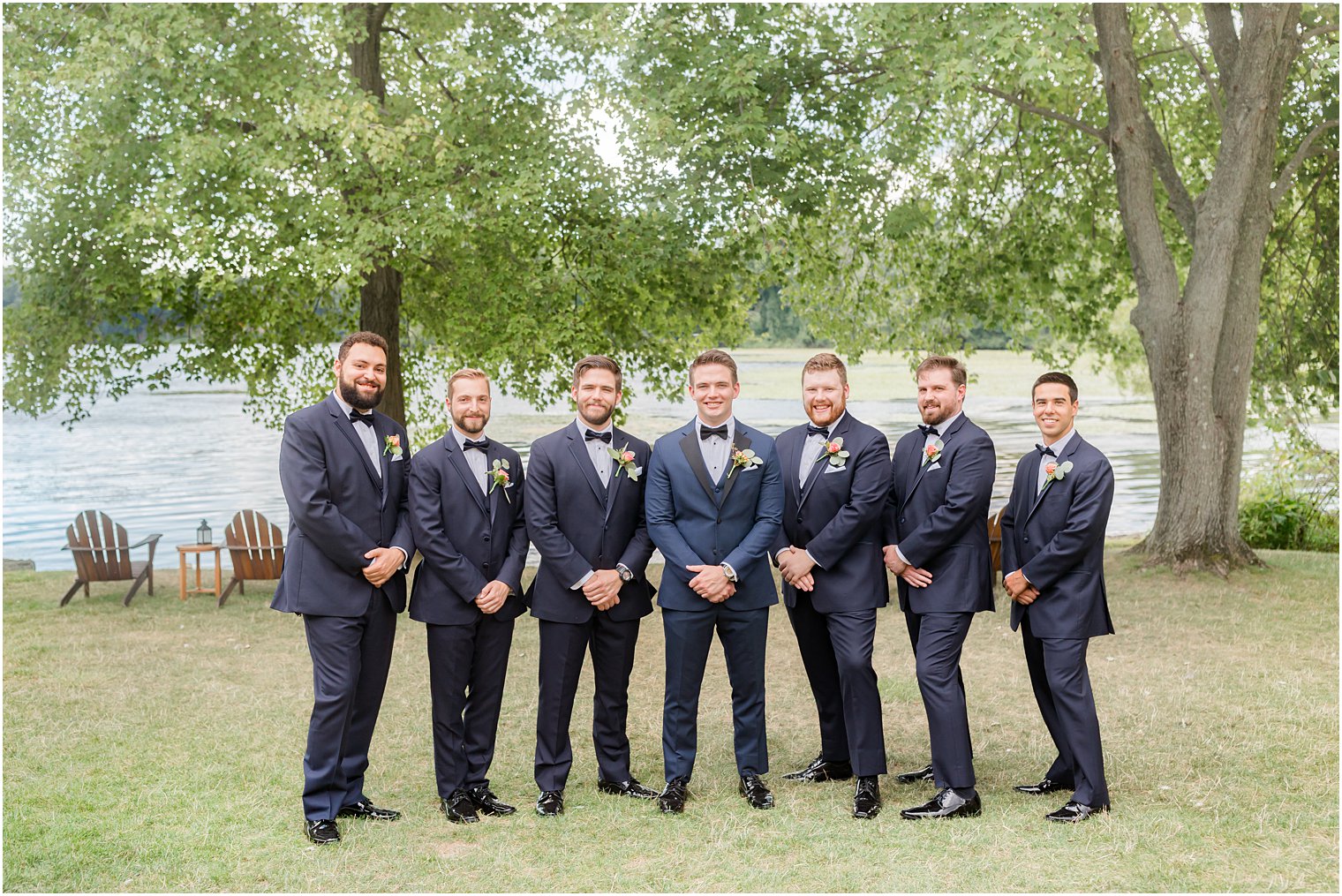 groom poses with groomsmen in navy suits at Indian Trail Club