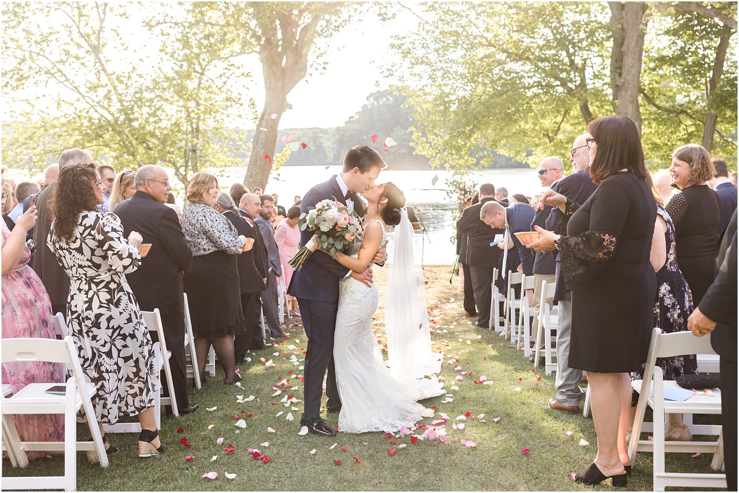 bride and groom kiss walking up aisle from outdoor wedding ceremony by water in Franklin Lakes NJ